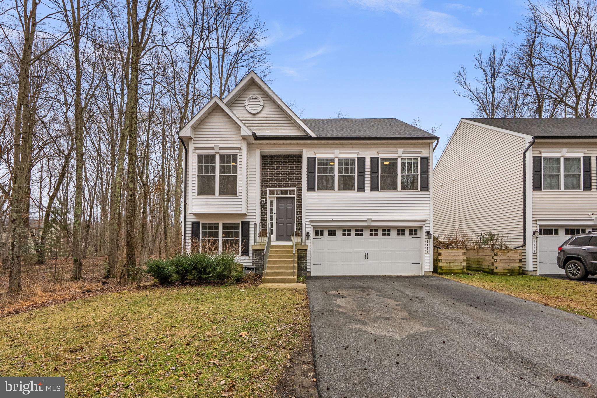 Price reduction!  This thoughtfully designed and 2022-built home blends modern finishes with a tranquil setting set against a backdrop of mature woods, creating a bright, open, and inviting space for both everyday living and entertaining.  An open two-story foyer welcomes you inside to the main living area with vaulted ceilings, while 9' ceilings throughout the rest of the home enhance the airy, open feel.  Charming cottage-style windows fill the space with natural light, and LVP flooring flows seamlessly through the living room, kitchen, and wide hallway to the bedrooms.  The kitchen features oil rubbed bronze fixtures, soft-close cabinets, granite countertops, and a center island with overhang for stools, plus space for a dining table. There is also potential for a deck off the back of the home, perfect for outdoor living.  The main level includes two secondary bedrooms and a spacious owner’s suite.  The secondary bedrooms feature custom molding, decorative wall trims, and stylish paint finishes—one accented with decorative peelable wallpaper—and share a hall bath with granite vanity and shower/tub combo.  Enjoy views of the wooded landscape from the owner’s suite, complete with two closets and a distinctive en-suite bath featuring dual sinks, granite countertops, a walk-in shower, custom wall trim accents, and removable wall covering.  The lower level provides a versatile living space, including a spacious recreation room with sliding glass doors to the backyard, a flexible 4th bedroom ideal for guests or an in-home office, and an additional full bath with granite vanity and shower/tub combo.  Raised garden beds just outside in the backyard and alongside the home are ideal for growing vegetables and flowers.