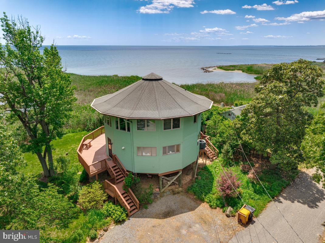 Fantastic opportunity to own your own land lighthouse-inspired round house with water views! Perfect serene retreat for the commuter and/or investment opportunity. Quiet neighborhood, blue heron sightings, and all the advantages of coastal living without the summer beach traffic. Freshly painted! This unique home features 3 bedrooms, 2 full bathrooms, an open-concept layout, and a spacious family room off the kitchen with no closed-off spaces — ideal for entertaining. Large windows surround the home, filling the interior with natural light and enhancing the panoramic water views. Wood floors flow throughout, adding warmth and character. Step outside to the wraparound deck, perfect for relaxing and taking in the dreamy scenery. Situated on a peninsula tucked between the Chesapeake Bay and 500 acres of state park, this property is currently enjoyed as a charming second-home retreat and part-time Airbnb. Come experience this one-of-a-kind home and incredible setting! Gated community offers a boat ramp, 2 private piers for fishing, crabbing, and boating, and a walking trail along the Bay.