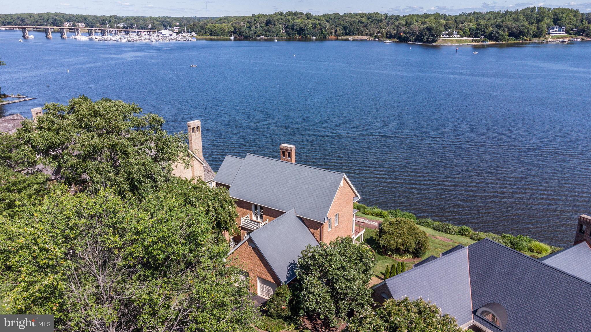 Enjoy resort-style living in this lovely brick home sited on the edge of the South River and only a few steps to a nature path and private sandy beach.  Other notable amenities in the desirable South River Landing community include a deep water marina, swimming pool and clubhouse off the protected waters of Almshouse Creek, tennis courts, playground and 24/7 gated and staffed security. This distinctive 4,650 sq. ft  home embodies natural light and panoramic water views from nearly every room, emphasized by abundant picture windows and tall ceilings. The lofty 2-story Great Room showcases a floor-to-ceiling, 2-sided fireplace which frames the South River.  Huge views are also captured from the Dining Room and the Morning Room off the Kitchen. A convenient shady covered deck is accessible from all social spaces and opens to a renovated and extended waterfront deck with cable railing. The main level Primary Suite features a sun-drenched super bath with cathedral ceiling, walk-in closet and private waterside deck. Handsome hardwood floors extend throughout most of the main level, including the Primary Suite, then up the wide staircase and upper level landing.  This hardwood bridge has a unique vantage point overlooking the front of the property and also the Great Room, while connecting the upper level bedrooms.  All 3 spacious, upper-level bedrooms enjoy a birds eye view of the South River. On the lower level, a vast Recreation Room with 9 ft ceilings can offer a variety of uses and highlights a 2-sided masonry fireplace, wet bar and a full-length wall of waterside windows and doors.  A full bath is tucked away for privacy and convenience while the 5th bedroom offers its own en suite bath and water views. The lower level opens to a covered flagstone waterfront patio to the grassy lawn. Significant storage space over the 2-car Garage is safely and easily accessible from a fixed staircase. (50-yr CertainTeed cedar-simulated composite roof and gutters in 2012) The community association fee covers your lawn mowing, mulching, trimming and snow removal while also maintaining the marina, pool, tennis, playground, nature path and 24/7/365 staffed gated security.  Boat slips for rent or purchase based on availability.