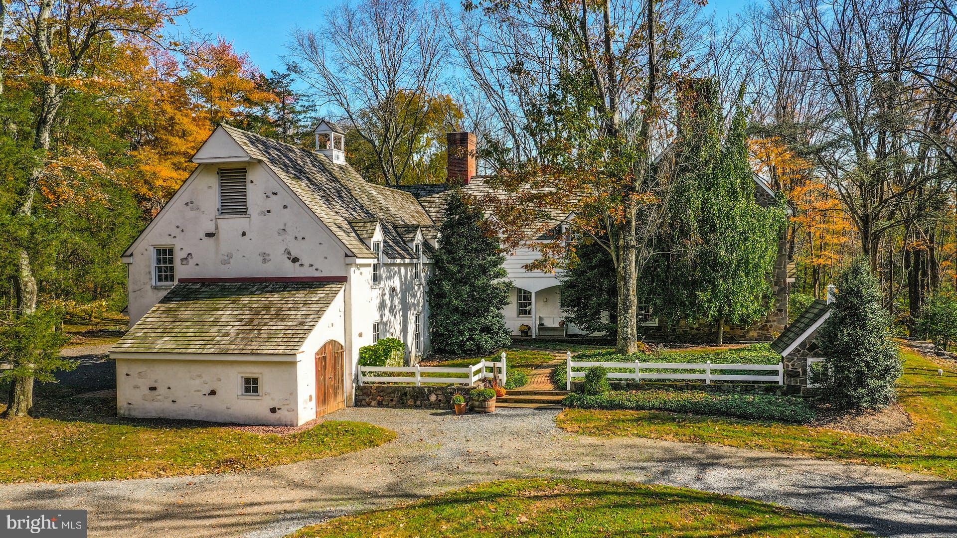 This elegant estate home is reminiscent of an English country manor, but was custom built in the 1970s by a prominent local family. The dramatic 4 acre wooded parcel is a stunning setting for the home, which includes an in-ground pool and unique barn space. With more than 5,700 square feet including six bedrooms, four and a half baths and an incredible eight fireplaces, Lower Mountain Manor is ideal for family, friends, and entertaining. Large rooms and high ceilings are defining features, along with pegged oak floors, abundant windows, and Delft tile. The spacious foyer opens to a large dining room, sunken living room, and office or library space with built-in shelves. Lots of storage and prep space is found in the eat-in kitchen, with Delft tile countertops and an island, as well as doors to two covered porches. Five main bedrooms upstairs include a luxurious primary suite with multiple closets, as well as another large suite and three hall bedrooms. A guest suite is accessible from this floor and has its own exterior entrance as well, with a private living room and bath. A 2-car attached garage has separate equipment space for hobbies or other vehicles. Across the driveway stands a large barn with massive doors that open to a lofted storage area, as well a 2-car garage and equipment bay.