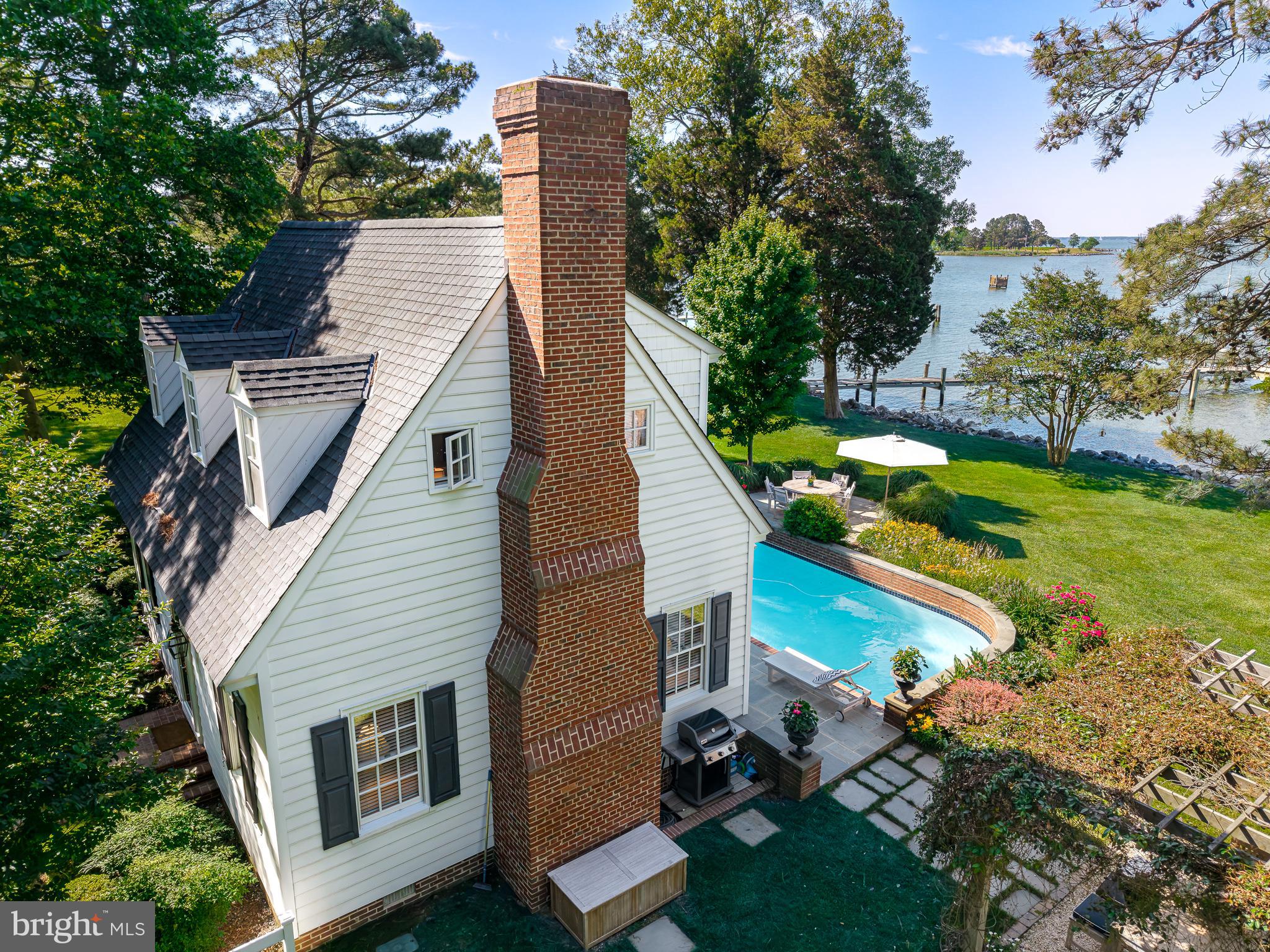 This exceptional waterfront cottage is set on two private acres and offers sweeping sunset views over the Choptank River to the Chesapeake Bay. Completely renovated from crawl space to roof, the home features over 2,600 square feet of beautifully finished living space with three bedrooms and three full baths. The interior showcases renovated kitchen and baths, complemented by extensive custom finish-work throughout. There is a detached garage with metal roof and second floor storage and gravel circular driveway with ample parking.  Improvements on this home include an encapsulated crawl space, new roof, siding, multiple premium sliding glass doors and windows, all valuable upgrades that enhance both style and energy efficiency. The grounds have been thoughtfully transformed with curated shrubs, trees, and perennials that highlight the existing landscape, concrete pool, and pergola, creating an ideal setting for outdoor relaxation and entertaining. Enjoy easy boating access just 10 minutes to Oxford and 15 minutes to Tilghman, while by land the property is ideally situated between Easton and St. Michaels. Enjoy the protection of high property elevation (no flood insurance required) with a sturdy rip-rapped shoreline and a private L pier with two new boat lifts. 24878 W. Ferry Neck Road offers the perfect blend of privacy, comfort, and Eastern Shore waterfront living on the Choptank River.  List of the many recent improvements in document section of this listing.