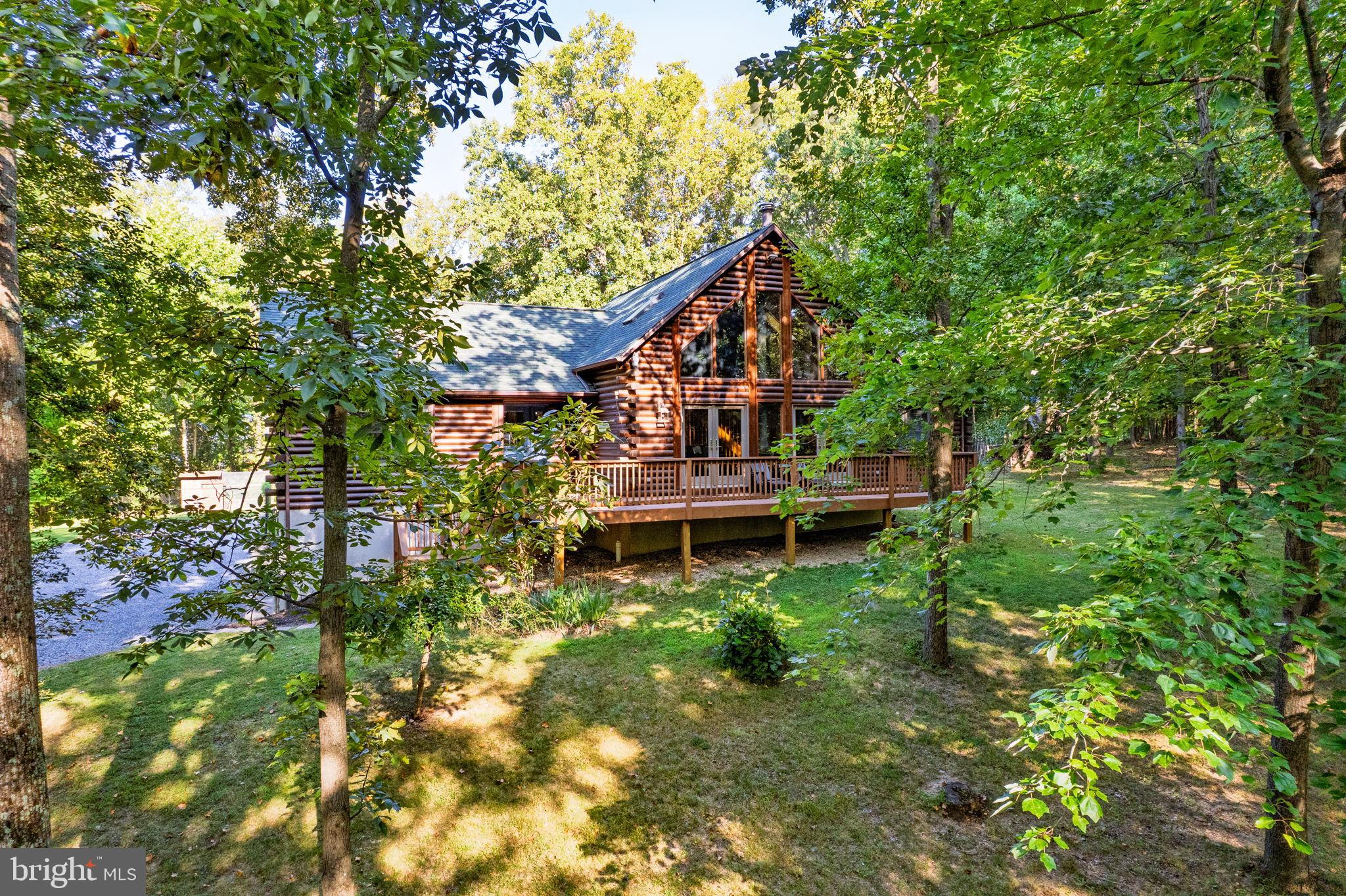 Step into your own private woodland retreat where a beautifully crafted log sided chalet rests on five acres of peaceful secluded forest bordering the Shannondale Springs Wildlife Management Area with more than 1,300 acres of protected land. Enjoy seasonal mountain ridge views of the wildlife area from the property, creating a rare and scenic setting.

The spacious family room makes an unforgettable first impression with its dramatic vaulted ceiling and massive windows that frame the surrounding trees while filling the home with sunlight. A wood burning stove creates a welcoming atmosphere perfect for quiet evenings. The country style kitchen features modern stainless appliances, a breakfast bar, and an adjoining dining space ideal for gatherings. The bedroom layout provides privacy for everyone. The primary suite is a true retreat with an updated bathroom and a cedar lined walk in closet.

Above the main living area, a loft offers endless possibilities as a home office, a fourth bedroom, a reading hideaway, or an open studio. The fully finished basement includes a large recreation room that works equally well for movie nights, fitness equipment, or gaming. Recent improvements include a new roof and well pressure tank installed in 2022 and a water conditioning system from 2021. A hybrid furnace offers the choice of electric, oil, or wood heat. Other features include  a SimpliSafe security system, a radon mitigation system, leaf guards on the gutters, a fire pit area, a fenced back yard, and a chicken coop.

Outdoor living is just as inviting with wide decks on both the front and back of the home for dining or relaxing. The gazebo with a ceiling fan offers shade on warm days and the hot tub is perfect for unwinding under the night sky. With direct access to nature trails and wildlife viewing plus convenience to commuting routes, shopping, dining, and entertainment, this property offers the perfect blend of privacy and accessibility.