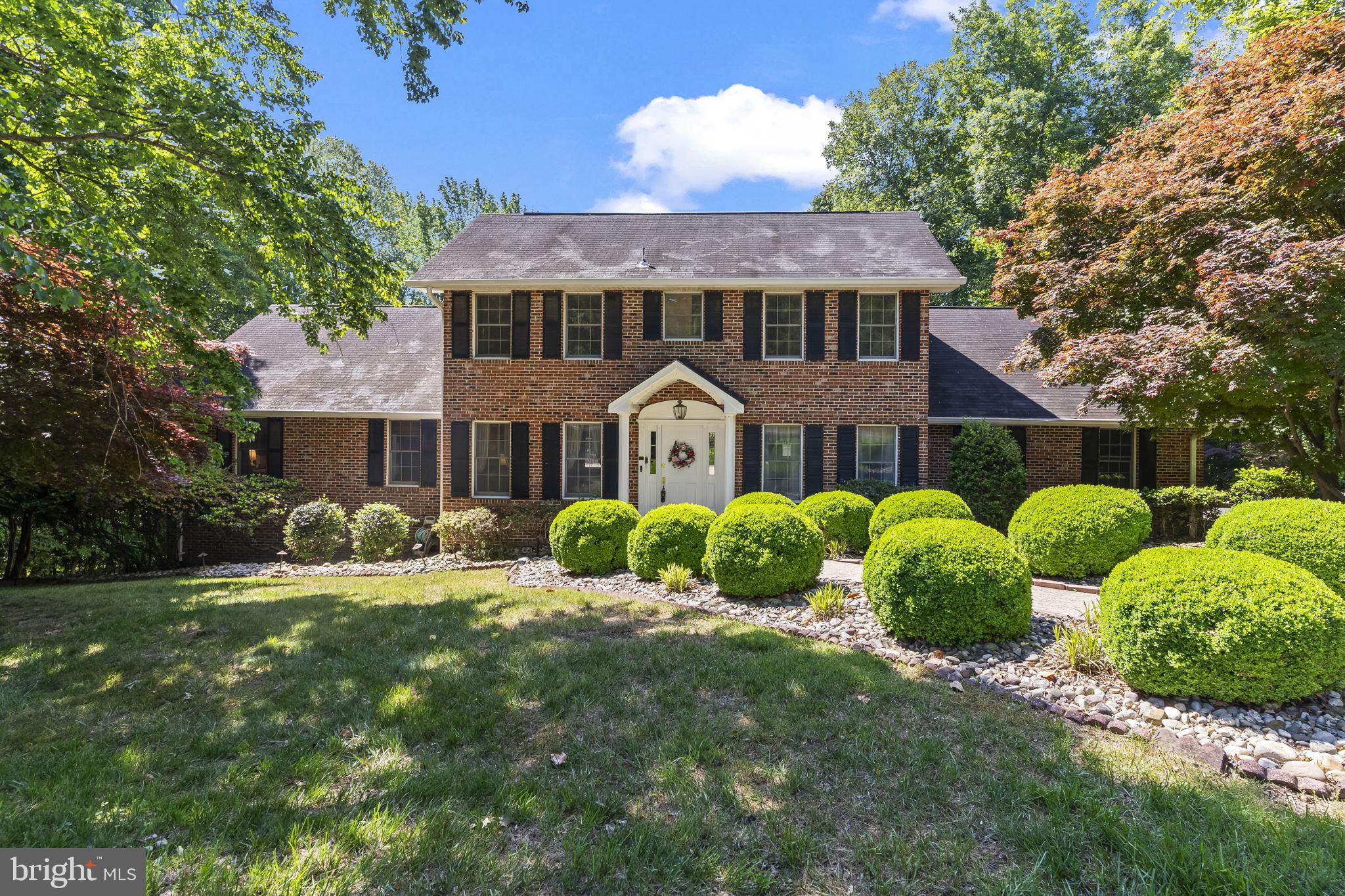 This beautifully maintained brick front Colonial offers the perfect blend of timeless elegance, thoughtful updates, and peaceful privacy, all tucked away on a quiet cul-de-sac setting on 2.03 wooded acres with NO HOA, allowing plenty of room for RVs, boats, trailers, and additional vehicles. From the side-load two-car garage and extended parking area to the expansive Trex deck overlooking the private backyard, this home is designed for both comfortable everyday living and effortless entertaining. Hardwood flooring flows throughout the main living areas, complemented by decorative crown molding, chair rail accents, and an inviting open layout filled with natural light.
The dramatic two-story family room is the true centerpiece of the home, featuring vaulted ceilings with exposed rafters, an impressive floor-to-ceiling brick fireplace with recently replaced gas insert, brick hearth and mantle, pendant lighting, ceiling fan, and second-story overlook. Sliding glass doors lead to the newly renovated 30x18 maintenance-free Trex deck with updated railings, creating an ideal indoor-outdoor lifestyle space.
The updated kitchen offers Corian countertops, stainless steel appliances, designer tile backsplash, recessed and pendant lighting, and oversized tile flooring that continues into the sunny breakfast nook with bay window. The main-level owner’s suite provides a private retreat with a renovated spa-inspired bath featuring skylight, oversized walk-in shower with body sprays, handheld wand, overhead showerhead, built-in dispensers, updated vanity, designer tile flooring, and walk-in closet with elegant French door entry. A second renovated full bath on the main level offers stylish finishes including vessel sink vanity, updated lighting, designer tile flooring, and glass tub enclosure.
Upstairs, two generously sized bedrooms each feature walk-in closets and access to large floored attic storage areas. There are two expansive attic spaces with flooring offering tremendous storage capacity and potential to be finished into additional playrooms, hobby spaces, or flex rooms for the kids. The bedrooms are connected by a Jack-and-Jill bath.
Additional highlights include an oversized laundry room with updated flooring, utility sink, added cabinetry, pantry, front-load washer and dryer, and side entrance to the driveway. The partially finished walkout basement expands the living space with updated LVP flooring, large recreation area, rough-in for a future bar and full bath, utility/storage space, and direct access to the oversized concrete patio beneath the deck. Additional updates include replacement garage doors, new well in 2018, new water holding tank in 2022, updated heat pump in 2024, newer dryer installed in October 2024, and whole-house fan for added efficiency.
Surrounded by mature woods for exceptional privacy while still conveniently located near shopping, dining, commuter routes, and local amenities, this exceptional property offers the rare combination of space, comfort, flexibility, and serene outdoor living.