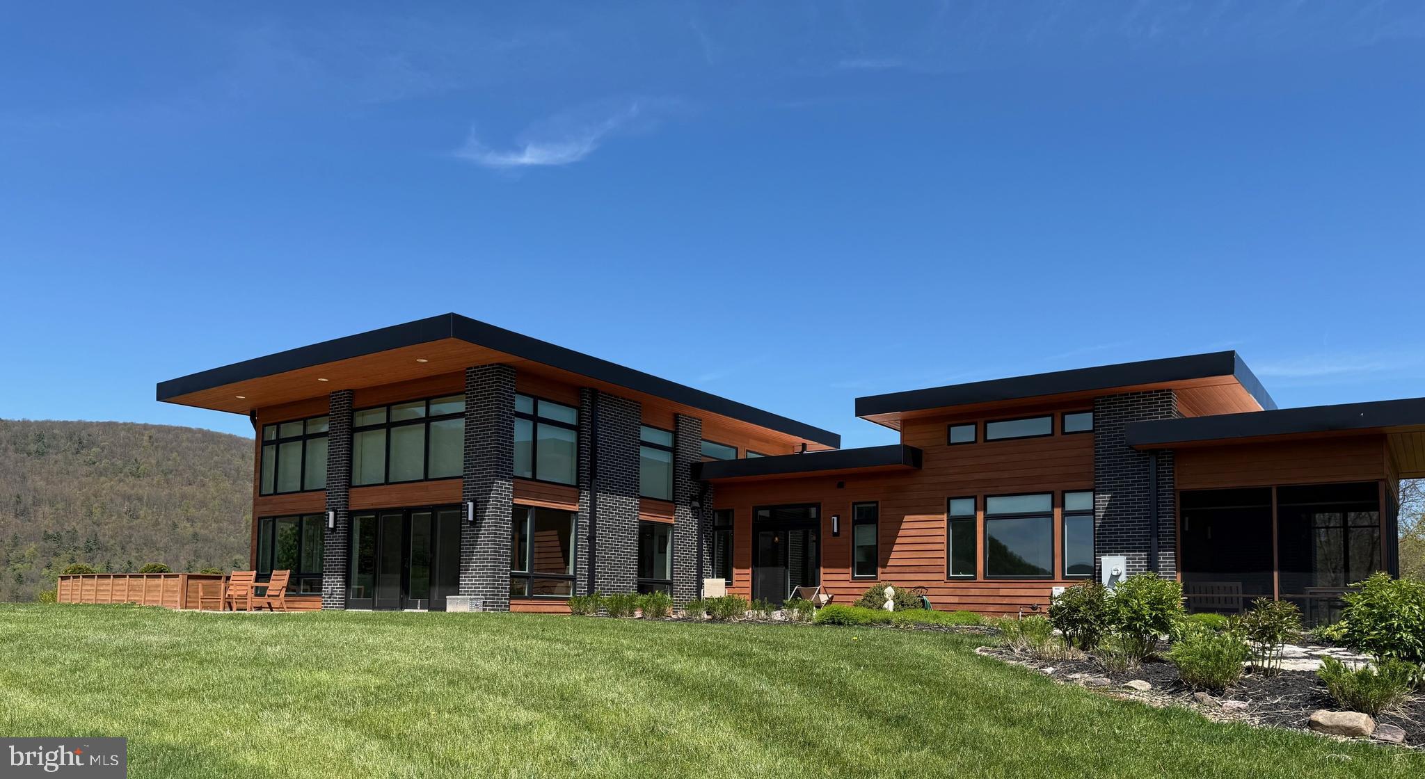 A truly one-of-a-kind architectural masterpiece set on over 23 private acres, this exceptional property offers a rare blend of luxury, craftsmanship, and serenity. Expertly built by Roeshot Construction Inc., this 3-bedroom, 2.5-bath residence is a private sanctuary immersed in nature. The striking exterior—featuring warm cedar siding paired with black obsidian brick and soft gray grout—sets an elegant tone from the moment you arrive.  A custom stone walkway, manicured gardens, and six distinct courtyard lighting zones create a dramatic and memorable entrance. Inside, you are welcomed by a breathtaking great room anchored by a floor-to-ceiling stone fireplace. A luminous garden room with skylights invites year-round greenery and natural light. Every detail has been carefully curated, from the Porcelanosa kitchen finishes and custom cabinetry to bespoke built-ins crafted by The Architect’s Millshop. Expansive sliding doors open to multiple patios, offering sweeping views of the Pennsylvania Wilds, along with the property’s koi pond, pool, and beautifully landscaped grounds.  Outdoor living is equally impressive, with an oversized cement patio capturing southwestern and western vistas, a cedar deck overlooking a tranquil garden, and a private garden retreat just off the primary suite framed by L-shaped planters. The fully irrigated organic garden and thriving orchard—featuring apple, peach, and pear trees—create a sustainable and picturesque setting.  Designed for efficiency and harmony with its surroundings, the home includes owned solar panels and radiant heating on both levels. Ideally located just eight miles from Bald Eagle State Park and Sayers Dam, this is a rare legacy property where refined living meets the beauty of nature.