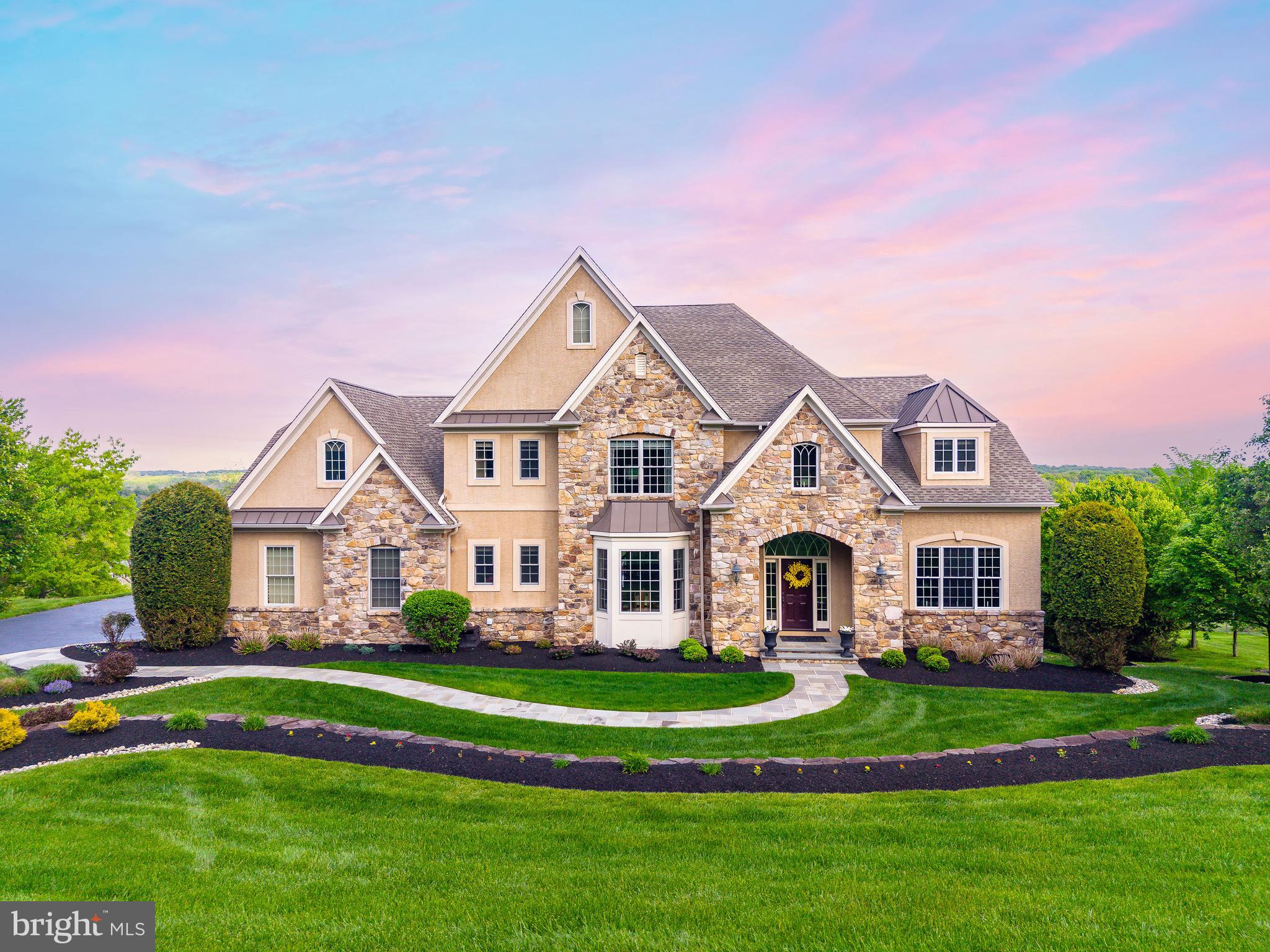 Welcome to 5829 Ridgeview Drive, a beautifully crafted estate home set on just over two acres in Buckingham Township and within the Blue-Ribbon Central Bucks School District. Elevated above the surrounding countryside, this property enjoys breathtaking, unobstructed views for miles, offering spectacular sunrises, dramatic skies, and a true sense of peace and privacy. Screened from the road and positioned high above the valley, the home commands a setting that is both serene and striking. The classic stone façade, manicured approach, and expansive grounds immediately convey quality and presence, while the elevated location ensures sweeping views from multiple vantage points throughout the home.
Upon entering, a gracious foyer with hardwood floors and a sweeping staircase sets the tone for the home’s timeless design. The main level flows effortlessly, offering generously proportioned formal and informal spaces filled with natural light. The great room serves as the heart of the home, an inviting space designed for gathering, relaxing, and entertaining, with expansive windows that frame the spectacular landscape beyond.
The kitchen is both functional and welcoming, featuring custom cabinetry, granite countertops, a large center island with seating, and high-end appliances, including two dishwashers for added convenience and ease when entertaining. Open sightlines connect the kitchen to the breakfast area, creating a seamless living experience. Just beyond, doors lead to the elevated deck, where the views become truly unforgettable. From this vantage point, rolling countryside and open sky stretch endlessly, an ideal setting for outdoor dining, entertaining, or simply taking in the quiet beauty of Bucks County.
A private home office with custom built-ins provides a comfortable and productive workspace, while additional main-level rooms offer flexibility for both everyday living and entertaining.
Upstairs, the primary bedroom suite is a tranquil retreat, featuring vaulted ceilings, abundant natural light, and stunning views across the valley. The en-suite bath is spa-inspired with dual vanities, a soaking tub, and a glass-enclosed shower. Additional bedrooms are generously sized, offering comfort, privacy, and ample closet space.
The fully finished lower level is a standout feature of the home, thoughtfully designed for recreation and entertaining. This expansive space includes a custom bar area, billiards and game spaces, and multiple areas for gathering and relaxation. A stone fireplace anchors the lower level, adding warmth and character, while a full bathroom enhances convenience for guests and entertaining.
A three-car garage, expansive driveway, and beautifully maintained grounds complete the property. Designed with both comfort and efficiency in mind, the home features a geothermal heating system that offers sustainable, cost-conscious living while maintaining a refined indoor environment year-round.
Ideally located just minutes from Doylestown Borough, New Hope, and major commuter routes, 5829 Ridgeview Drive offers the rare combination of privacy, elevated views, and refined living in one of Bucks County’s most desirable settings. This is a home where the views define the experience, offering a sense of retreat, beauty, and timeless elegance in every season.