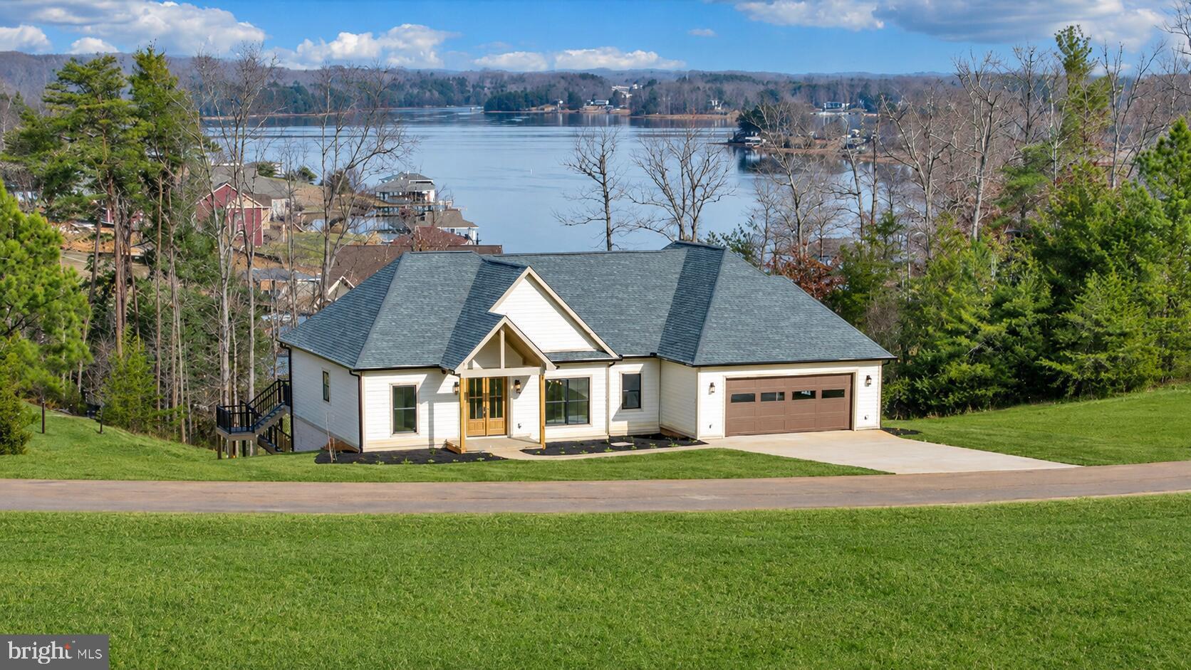 Located in the prestigious community of Compass Cove, this brand-new home offers lake and mountain views and sits on a highly desired deep-water no-wake cove. Complete with designer, top-quality finishes and custom woodwork throughout, the home features a soaring vaulted entry with wood ceilings, built-ins flanking a gas fireplace, and a covered rear porch with a high wood-lined ceiling. The kitchen showcases a custom cabinets, wood vent hood, gas range, large island, and a butler's pantry with built-in shelving and detailed wood trim. The main-level primary suite includes a custom coffered ceiling, wainscoting, a walk-in tiled shower, and a beautifully designed custom closet. Two additional bedrooms and a stylish tiled bath complete the main level. The finished walkout terrace level offers a full second kitchen, theatre room, gym, recreation area, and two additional bedrooms. Perfect for multigenerational living or entertainment space. Walk out to your covered patio, fire pit area, and a concrete path with a gentle walk down to your private dock. A boat house provides storage, and the deep water at the shoreline is ideal for swimming and boating. Public water, premium finishes, and a well-designed floor plan make this a unique opportunity to enjoy a luxurious lakeside retreat in one of the lake's most prestigious communities. Start living the lake dream!