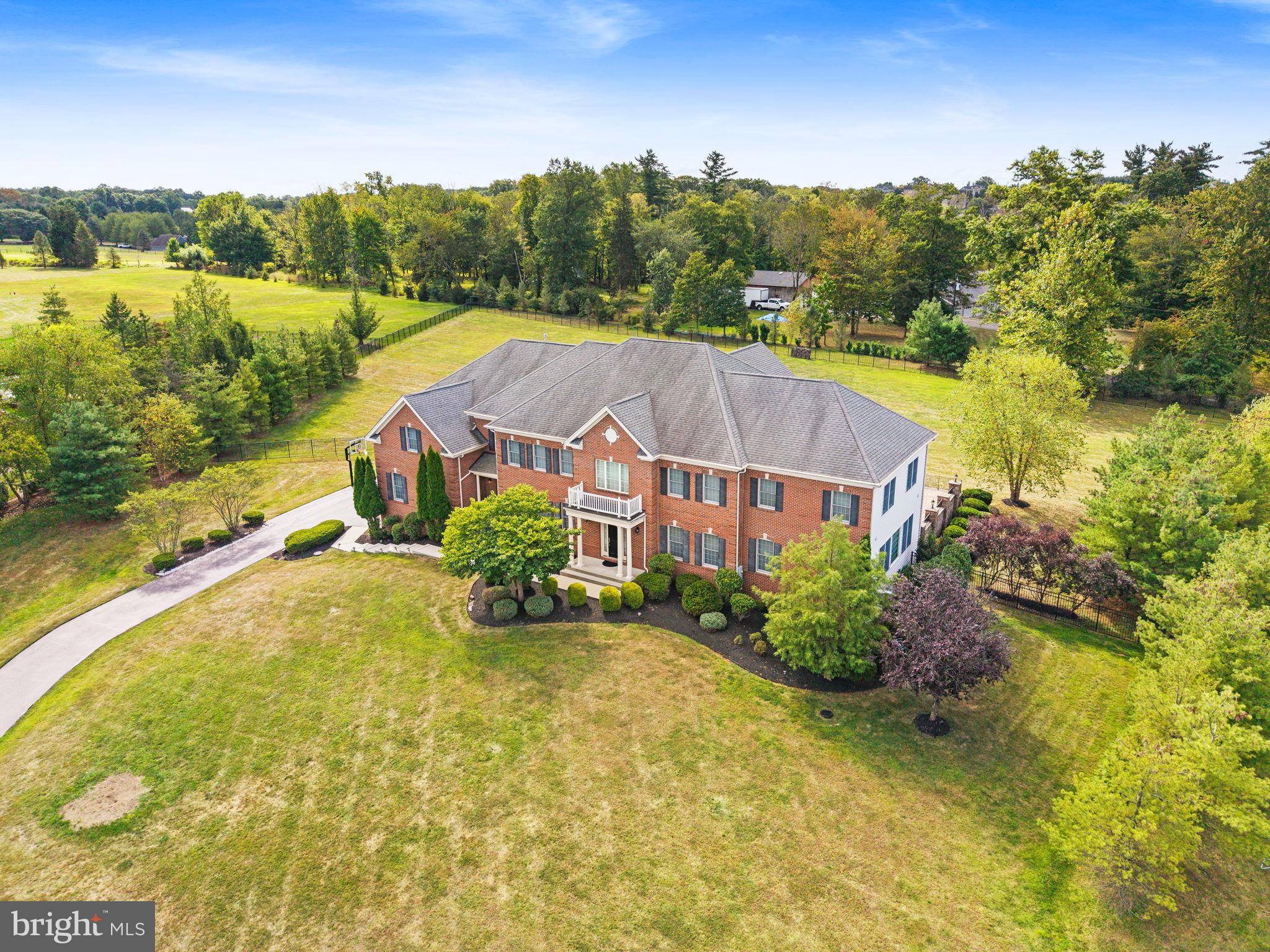 This distinguished home in Matthews Ridge presents an exceptional opportunity, offering over $800,000 in structural upgrades. The stately exterior features a combination of brick and beaded siding. Inside, the open and expansive floor plan is highlighted by 10-foot ceilings on the first floor and 9-foot ceilings upstairs, enhancing the sense of grandeur throughout. Situated on a premium lot exceeding two acres, the property includes an expanded two-story Great Room, an enlarged Conservatory with a bar and a Bonus Room above, and a spacious Gourmet Kitchen equipped with a serving bar—ideal for entertaining. Functional amenities include a Mudroom with built-in cubbies for storage, and five bedrooms on the second floor, each appointed with a private full bath. Additional features comprise a chandelier lift and a four-car garage with wonderfully high ceilings to accommodate car lifts or extra storage needs. The finished walk-up Lower Level offers further expanded living space with a bar, bonus room, and full bath. Outdoors, the extensive multi-level paver patio features a built-in grill, outdoor speakers, multiple seating areas along the home's length, and a wood-burning fireplace—perfect for hosting gatherings or recreational activities within the completely fenced, 375-foot-long backyard. This picturesque community has the added advantage of no homeowner's association. Residents benefit from the convenient location in Wrightstown Township, which provides lower taxes and access to Sol Feinstone Elementary within the highly desired Council Rock School District.