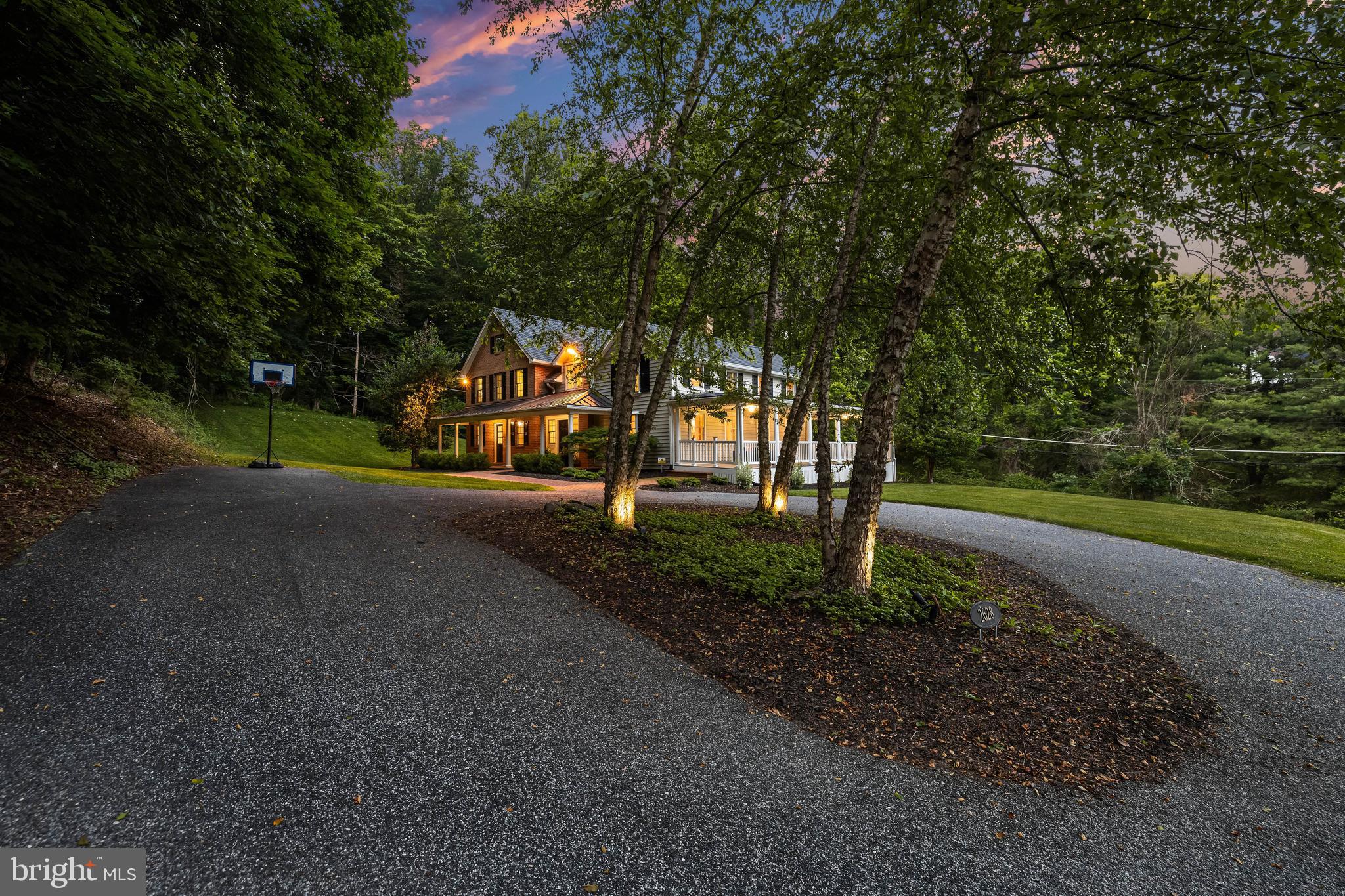 There are homes in Greenspring Valley, and then there is this one. A 1921 original on a private drive, set well back from the road behind a canopy of mature trees, 2628 Greenspring Valley Road offers something increasingly rare at this price point: genuine seclusion with a prestigious address, adjacent to Greenspring Valley Country Club and minutes from everything Baltimore has to offer.
The home's signature feature is a wraparound porch measuring an impressive 40 by 38 feet, meticulously rebuilt in 2019 with new flooring. At this scale, it is not an amenity. It is a room. Morning coffee, evening entertaining, quiet afternoons with a book. This porch becomes the heart of the home from the first warm day of spring through the last of fall.
Step inside to a main level with exceptional flow and versatility, where sun-drenched rooms transition naturally between everyday living and gracious entertaining. Two fireplaces anchor the main level, generous windows flood every room with natural light, and updated kitchen appliances (2024) and a water softening system (2022) deliver the modern comfort the bones of this home deserve. Upstairs, four generously proportioned bedrooms include a primary suite with a spa-like bath.
For the buyer who wants to build equity from day one, the nearly 1,500-square-foot unfinished walkout lower level is where it happens. Finished, this space brings total square footage to approximately 5,000 feet. The vision is yours. The value is already here.