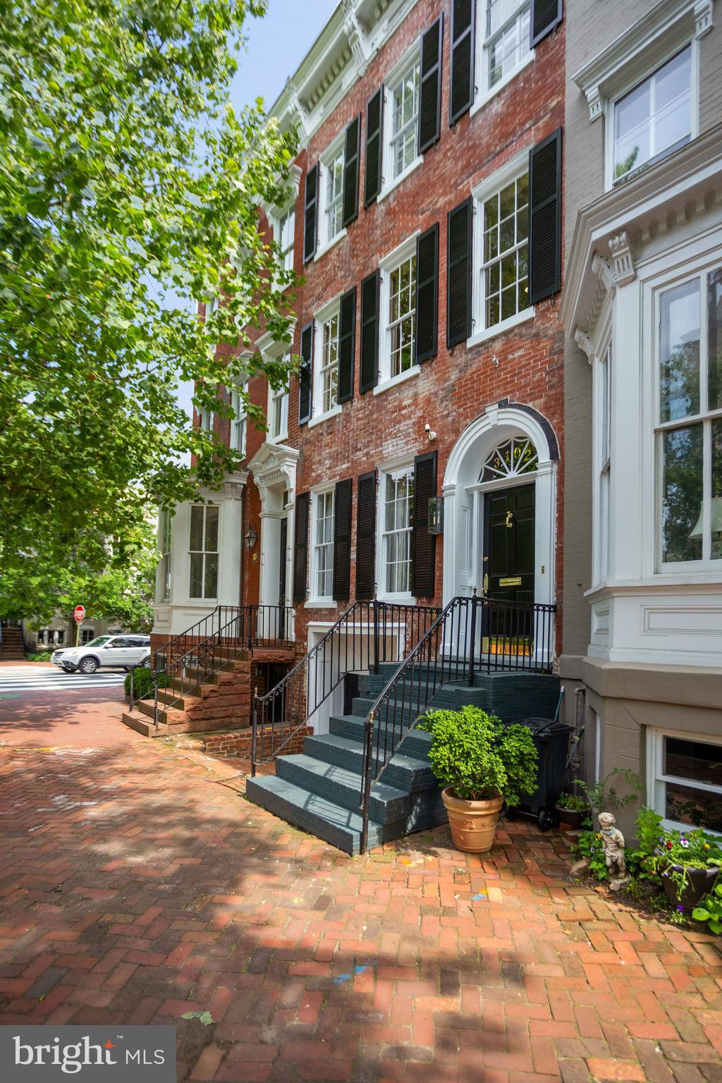 This tastefully renovated and flawlessly redesigned townhouse is located in the heart of Georgetown's East Village, just blocks away from shops, restaurants and entertainment. Features throughout include high ceilings, hardwood floors, original details, and generous rooms with large windows flooding every space with natural light. Beautifully renovated by Chryssa Wolfe in 2016 with high-end finishes throughout, this home showcases a generous Entry Hall, double Living Room with matching wood-burning fireplaces, Dining Room with built-in banquette seating and Wet Bar, and Chef's Kitchen with marble countertops and SubZero and Wolfe appliances; both Dining and Kitchen feature their own set of French doors to gorgeous rear Garden with fireplace. Upper Level features gracious Owner Suite with 3 deep double closets and Waterworks en-suite Full Bath with Carrera marble counters, Bedroom / Upstairs Den with wood-burning fireplace.  Leading to Third Level is a large, south-facing Sun Deck with views of Georgetown gardens. Bedroom #1 and #2 feature decorative fireplaces and share an updated white Kohler Full Bath. Lower Level features additional Family Room with vinyl wood flooring, Full Bath with shower and marble countertops, Kitchenette with stainless steel appliances, Laundry Area, and access to full-size 1-car Garage.
