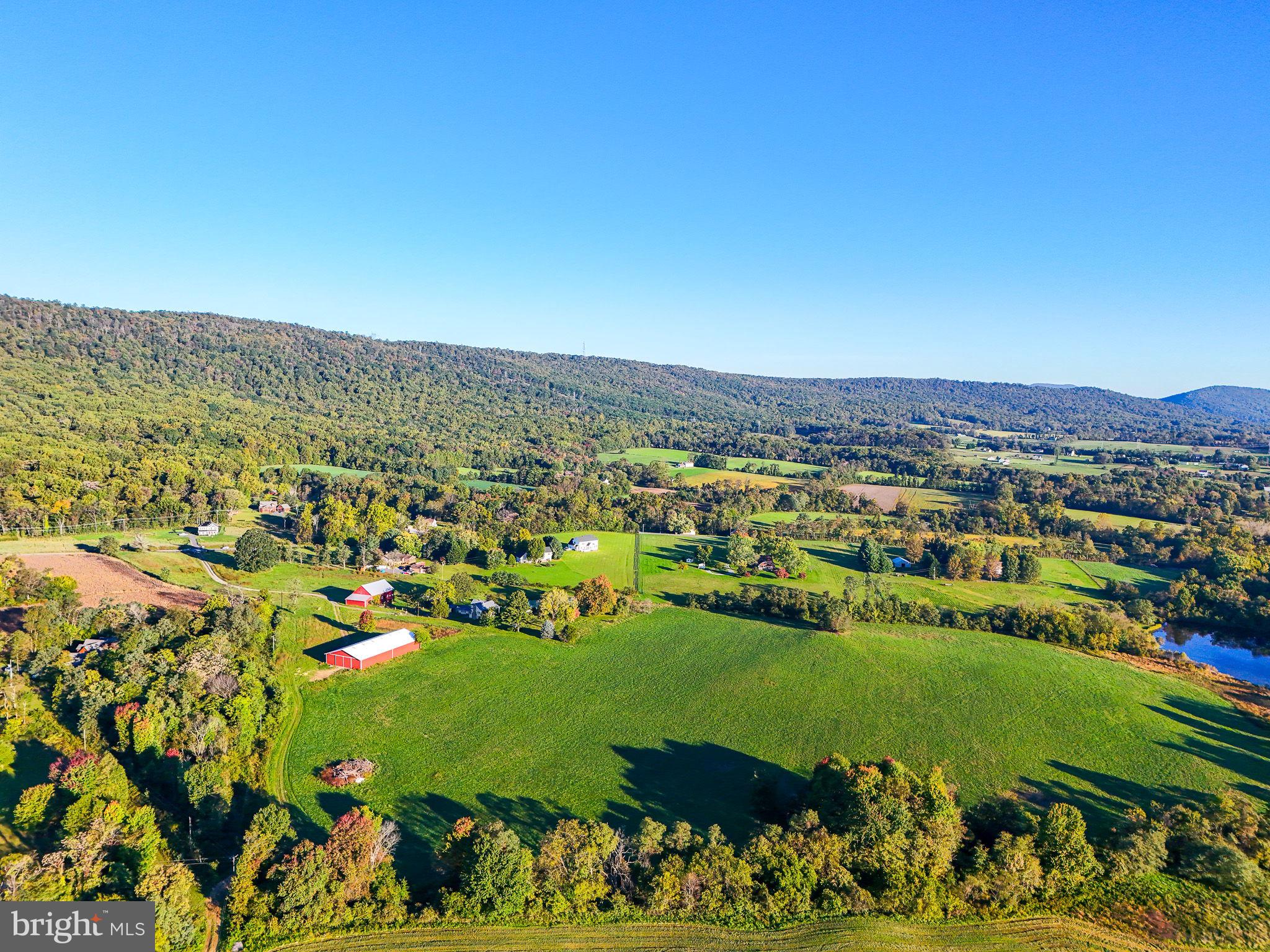 At last, a beautiful 50+/- acre parcel for your equestrian estate has come on the market!  This is an idyllic setting with gently rolling farm land, two spring-fed ponds and stunning mountain views.   Bring your builder to explore the old farmhouse for possible renovation.   The newer Morton building is in very good condition and sits nicely on a small rise overlooking much of the property.   Other improvements include an old bank barn, a stone spring house by the smaller pond, shed and a large farmhouse all need varying degrees of repair/maintenance.   With 50 acres and frontage on two roads,hamlet/cluster subdivision may be possible; please explore with the County.   Well and septic support old house.    Property is in land use; Seller will not be responsible for roll back taxes, if any.   Seller does not have a survey.   Buyer is responsible to verify the exact acreage.  Improvements are sold As Is.
