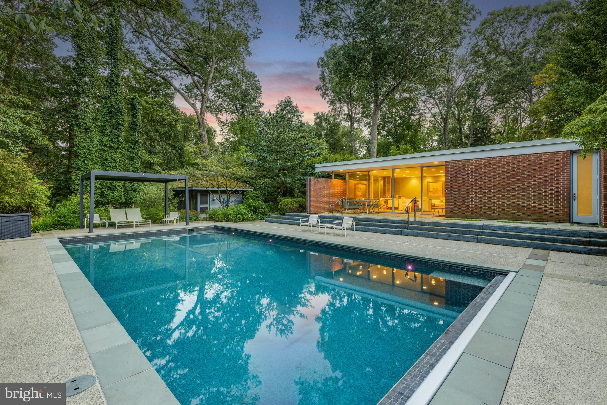 Live authentically. Welcome to Camp WabiSabi. One-level living finds its purest form in this remarkable mid-century estate, where walls of glass, more than thirty skylights, and an open floor plan create luminous interiors that flow effortlessly. Nearly every space frames views of mature gardens—decades in the making—whose seasonal waves of color animate the landscape from spring through summer and into fall. A design that unites interiors with expansive exteriors—an entertainer’s dream anchored by a chef’s kitchen ripe for culinary artistry. Wake up to glistening water views and a koi pond just steps from your bed. Let the zen infuse your soul. The primary suite offers a fireside sitting room, spa-inspired bath, generous closets, and a clever swiveling television tucked into custom millwork. Bespoke cabinetry and bookshelves enrich nearly every room, while a sauna provides restorative retreat. A shimmering pool, three reflective ponds, and winding stone paths accented by David Hess’s sculptural railings and gates, invite exploration and provide an outdoor oasis. Eat fresh out of your garden with herbs and vegetables in three raised garden beds. The quintessential barn has much potential. This property includes a second deed. Verizon Fios Internet. Cultivate your existence. The art of uniting human and home.