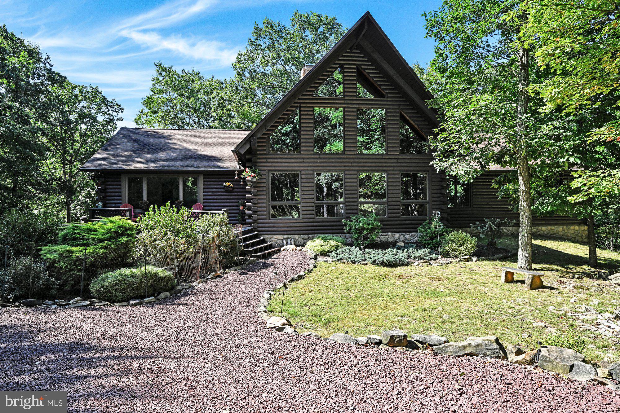 THIS is the one you have been waiting for!! Serenity & Splendor at one address!! A retreat for all seasons to celebrate & enjoy life!!  Nature Lover's Delight! Personal Paradise! Vacation Getaway! Snowbird Summer Stay! Options are yours!! This serene & pristine beauty snuggled on 1.8 acres in a private community offers an instant invitation to escape the hustle & bustle power grid of life!  This timeless contemporary log home with modern amenities  & gracious formality is situated 160' from the road overlooks a breathtaking green area  & radiates tranquility and a calming ambiance that offers a welcome invitation to unwind.  The log exterior blends harmoniously into the natural surroundings. A circular driveway welcomes you home & offers plenty of parking for family & guests. A two-tiered deck & welcoming front door ( a house warming gift from the late great actress Mary Tyler Moore & her husband Robert) greets you! A two story entry creates an impressive introduction  to this architecturally blessed home  with a harvest of features. The soaring chalet-style great room features a vaulted ceiling, beams, a wall of thermal pane windows to watch the artwork of nature change with the seasons. A 5x9x23' field stone fireplace with rough hewn mantle & a few coins embedded in the stonework for luck anchors the great room & will have you wishing for a stay at home snow day. A sweeping staircase to the right of the fireplace ascends to the stunning18x24'raised roof loft dressed w/furnishings that remain, a stone fireplace, double balcony that overlooks the great room, & offers a private haven that could be utilized as a library, family room, office, or additional sleeping quarters. A beamed ceiling caps the dining lounge at the rear of the great room and is perfect for early morning coffee or family dining.  The 15 x 20 formal dining room perfectly embraces the union of wood & glass is ready for candlelight & wine dinners or large parties & celebrations. The 14 x 14 kitchen is beautifully acquainted with granite counters, an abundance of cabinetry including a built-in desk, and a center island snack bar that enables great interaction between guests & cooks. A laundry room & half bath add convenience to the main living area.  A center hall to the right of the great room offers a pull down for access to an 8 x 24' storage attic.  The tranquil owner's suite with ensuite bath balances escapism with everyday comfort.  Large windows allow natural light & pretty views from the 2 additional bedrooms on the main floor.  The garden level offers an 840 sq ft APARTMENT/SUITE complete with a kitchen, large & bright living rm, dining area, full bath, 2 bedrooms, a private entry with recent Anderson sliders that open onto an 8 x 22 deck complete with a swing for solace & enjoyment- great for extended family or guests. A 20x20 twin door garage, utility room, workshop, storage room and a 15 x24 game room complete the lower level. A 76 foot deck compliments the rear of the home & offers the perfect place to sip your favorite cocktail, dine outdoors or simply relax &  enjoy nature's beauty. A zen-like garden embraces the screened gazebo (complete with ceiling fan & outlets)  invites you to reflect  & relax. Current owner installed oil heat, new hot water tank, Mini-split units, granite counters,  Anderson slider doors & so much more! Commuter Friendly about:7 miles from Inter. 81; 138 miles from New York; 108 miles from Phila; 74 miles from Harrisburg; 60 miles from Allentown & an easy commute to Pocono attractions.  Escape the ordinary & enter the serenity of trees & flowering paths  that surround the sanctuary of your new home!  Why wish & wait when you can own this Dream Home!! Create your new traditions & memories here!!