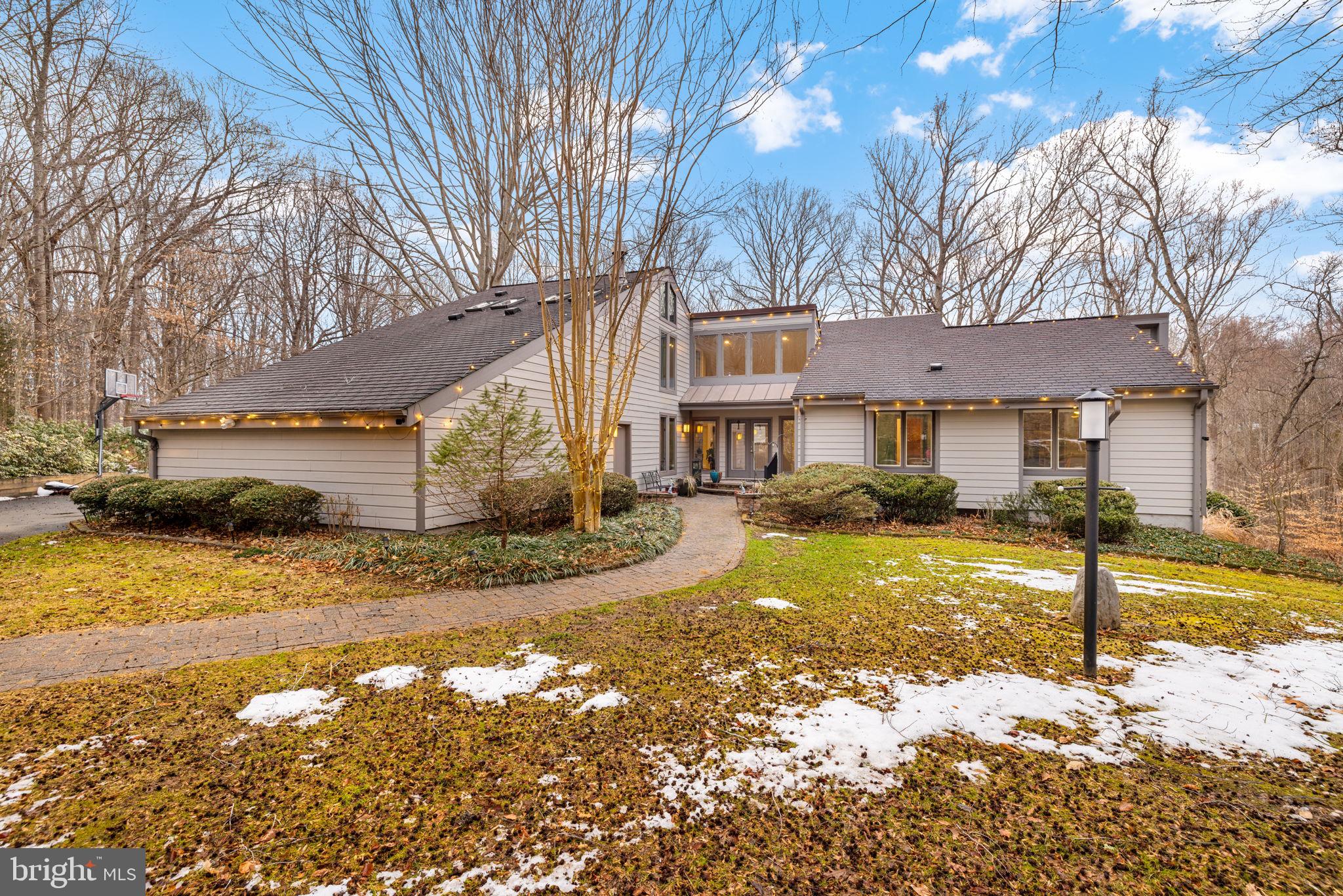 Architectural drama meets a private five-acre retreat. This spectacular, one-of-a-kind contemporary blends architecture and nature in perfect harmony. Privately sited on five serene acres with a picturesque babbling brook along the rear, this exceptional residence offers resort-style living with remarkable privacy.

Designed for both grand entertaining and comfortable everyday living, the outdoor spaces are truly special. The property features a heated in-ground pool, gazebo, expansive entertaining deck, stone patio and walkways, fully equipped outdoor kitchen, generous guest parking, and a storage shed with electricity.

Inside, walls of windows frame peaceful wooded views while dramatic open spaces create an unforgettable first impression. The home offers five bedrooms and four full baths, including the highly sought-after advantage of two primary suites.

The main-level primary suite is ideal for convenience and comfort, featuring hardwood floors, serene wooded views, a beautifully remodeled luxury bath with double sinks, and a spacious walk-in closet with organizers. The upper-level primary suite occupies the entire top floor and serves as a private retreat with vaulted ceilings, hardwood floors, a private balcony overlooking the wooded landscape and a walk-in closet. The upper-level primary bath features skylights that flood the space with natural light, double vanities, a soaking tub and a separate shower.

At the heart of the home, the dramatic two-story great room showcases a soaring ceiling, gas fireplace, and balcony overlook, creating a stunning architectural focal point. Just off the family room, a hidden wet bar with custom storage drawers adds both function and an element of surprise.

The beautifully remodeled kitchen features soft-close cabinetry, granite countertops, stainless steel appliances including a built-in microwave and induction cooktop, and convenient slide-out shelving for optimal storage and organization. The oversized breakfast room is filled with natural light and features double sliding glass doors that open directly to the outdoor kitchen, creating a seamless indoor-outdoor entertaining experience.

The enormous walk-out lower level is designed for entertaining and opens to the backyard and pool through multiple sliding glass doors. This level includes an expansive recreation room with gas fireplace, an oversized wet bar, a private sauna, a fifth bedroom with walk-in closet and hidden office nook, a full bath, a flexible den ideal for an office or exercise room, and a massive storage room. 

Additional highlights include dual-zone heating and cooling, Andersen double-pane windows, HardiePlank siding, a backup generator, and an oversized two-car garage with dedicated workshop space.

 This exceptional estate captures the serenity of country living while remaining just off Route 123 and the Fairfax County Parkway, offering effortless access to major commuting routes, shopping, and dining throughout Northern Virginia.