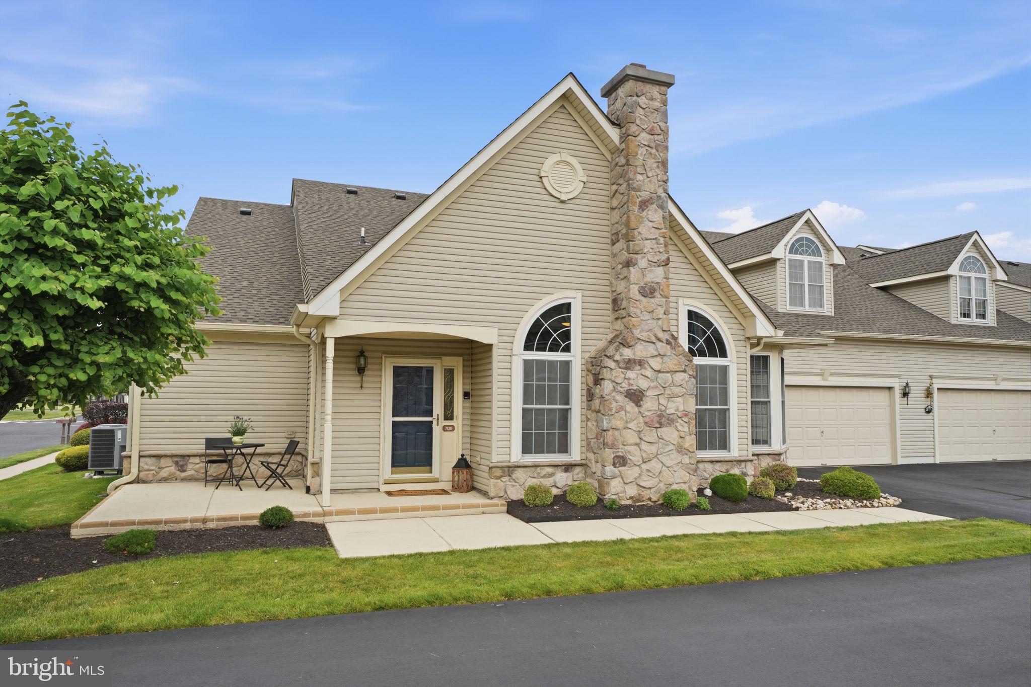 Welcome to 709 Daylily Drive, a desirable Mulberry Model quad home in the popular 55+ community of Flowers Mill. A spacious patio welcomes you as you approach the covered front entrance. Inside, you are greeted by a bright and inviting combination living and dining room featuring vaulted ceilings, hardwood flooring, a gas fireplace, and recessed high-hat lighting that enhances the home's warm and open feel.  The adjoining kitchen offers stainless steel refrigerator, a pantry, and a cheerful breakfast nook with large windows. Conveniently located just off the kitchen are the first-floor laundry room and access to the attached two-car garage, making daily tasks and unloading groceries effortless.  The main level also features a generously sized primary suite complete with a tray ceiling, walk-in closet, additional double closet, and an en-suite bathroom with stall shower, double sinks and linen closet. Recessed high-hat lighting continues into both bedrooms, providing a bright and updated atmosphere throughout the home.  While designed for the ease and convenience of one-story living, this home offers exceptional flexibility with a large finished loft and a third full bathroom. Whether used as a private guest suite, home office, hobby studio, playroom for grandchildren, or simply valuable storage space, this versatile area can easily adapt to your needs.  Major updates include a new roof in 2022 and a new HVAC system in 2023, providing peace of mind for years to come.  Residents of Flowers Mill enjoy an exceptional lifestyle with access to a clubhouse, indoor and outdoor pools, new tennis and pickleball courts, and a vibrant calendar of social activities and community events.