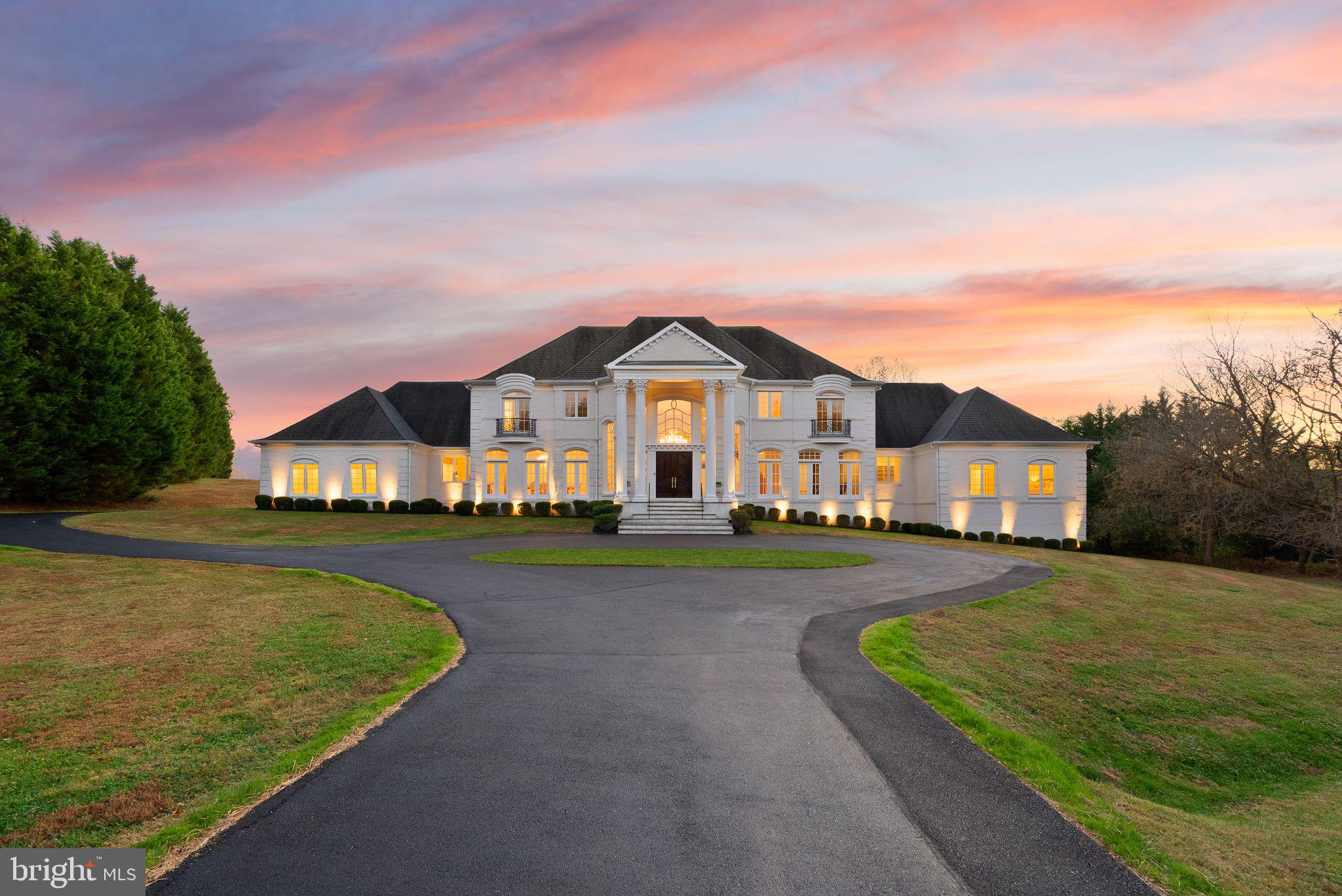 Private 4+ acre estate designed by renowned architect John Neufeld, offering over 12,000 sqft of refined living space and two attached garages with parking for four. A grand, gated entrance leads to the stately residence set back from the road, with an impressive columned façade and elegant oversized wood doors that open into a soaring 2-story marble foyer. From the moment you step inside, your eye is drawn straight through to the rear wall of windows showcasing gorgeous views of the grounds—emphasizing the estate’s privacy and scenic surroundings. Custom craftsmanship is evident throughout, from iron balustrades and intricate crown and wall moldings to imported Italian marble. The main-level primary wing is a true retreat, featuring two oversized custom walk-in closets and a spa-inspired bath with Italian marble floors, dual vanities, an Italian marble walk-in shower with four shower heads, a soaking tub, and a private water closet. The upper level offers four additional bedrooms and three full baths, including two en-suites. Juliet balconies and Italian marble baths elevate the space and provide excellent flexibility for guests or family living. At the heart of the home, the dramatic living room impresses with a 20-foot ceiling, expansive wall of windows, gas marble fireplace, and beautiful picture-frame moldings. A handsome main-level office and a comfortable family room with a marble wood-burning fireplace create inviting spaces for everyday living. The formal dining room with French doors is ideal for entertaining, while the gourmet kitchen is perfectly equipped for both chefs and home cooks, featuring a Thermador 6-burner + grill gas cooktop, oversized Sub-Zero refrigerator, double wall ovens, built-in microwave, large center island with prep sink, and a spacious breakfast room that opens to the rear patio. Dual staircases to both the upper and lower levels, with the lower level offering an exceptional opportunity—fully framed with a plumbing rough-in, large bay window, walk-out rear access, and a footprint that can accommodate anything you envision: recreation spaces, a home theater, fitness center, guest suite—the possibilities are endless. Two side-loading garages open into a generous mudroom with a separate entry, laundry area, workstation, abundant storage, coat closet, and an oversized pantry. Additional parking is plentiful, with both a side driveway and a circular driveway. 4-zoned HVAC. Every room offers serene views of the stunning property. This estate is a true Potomac masterpiece!
