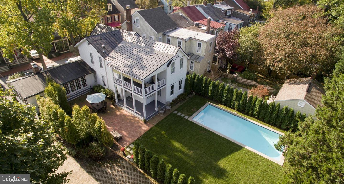 Truly one of the finest homes in all of the Historic District.  Sprawling over three city lots, this property boasts one of the largest parcels in downtown Annapolis.   Originally built in  1862 and known as the Jickling House, this Queen Anne style dwelling  was enlarged several times and a  carriage house was added in 1891.  The back of the property is accessed by a motorized gate and  features a long stone driveway accommodating six plus cars.  Additionally you'll find large brick patio, lovely English garden, inviting covered double deck porch overlooking a newly refurbished and heated saltwater pool along with carriage house/garage. The home has been meticulously restored and is as much of a work of art as it is a modern fully functional residence.  Exquisite architectural details are seen in the moldings throughout the house and stunning curved staircase.   You'll find the large open kitchen/great room with Viking appliances and a 13' foot island is ideal for entertaining as is the elegant dining room and convenient butler's pantry.   Upstairs is a magnificent master bedroom suite  with hand hewn beams and cathedral ceilings along with motorized shades, custom built-in window seats and direct access to a picturesque balcony.  There are currently two offices in the main dwelling, top level security and home automation along with a  gorgeous guest suite with  a newly installed mini kitchen in the carriage house which houses the 5th bedroom and 3rd full bath.   All of this and just steps to Main Street and downtown Annapolis and a block and a half from Spa Creek and a variety of water related activities.
