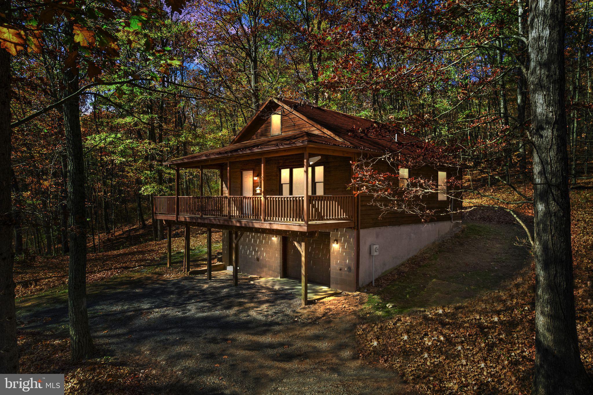 Welcome to 2300 Wardensville Pike, in gorgeous Star Tannery, VA. This home sits on 6.25 private acres providing a peaceful retreat that can be used for full-time living, short-term rental/vacation home, or even a hunting cabin. This property backs directly to the George Washington National Forest, sits close to the Tuscarora Trail Head, and is a short drive to both Wardensville, WV and Strasburg, VA. Easy access to Interstate 81 allows for easy commuting to and from the home. Nestled amongst the trees, this home provides gorgeous views from the covered porch and a 1-car garage with interior access. The main level of the home provides an open concept living room, dining area, and kitchen space filled with incredible, natural light. A free-standing wood-burning stove provides warmth during the cold, snowy months. The kitchen is large and has ample storage and prep space. Two generous bedrooms on the main level share a full bathroom with a tub/shower combination. Convenient, interior access to the lower level brings you to a finished space, perfect for a gym, downstairs den, or a flex space. A full bathroom and a laundry area complete the finished portion of the lower level. In the main-level living room, there is interior access to the upper level attic space that is ready to finish, providing many options for additional flex space for whatever you can imagine. The ductless mini-split system was installed in 2021 and provides 4 individual zones of heat and A/C  with thermostat remote controls in each area. The system will allow for one additional line that could be run to the upper level attic area. The 1-car garage has interior access and is great for a workshop/storage space as well. In 2023, a generator ready box/hookup was installed, providing easy plug and go power from a portable generator. Other recent upgrades: hot water heater (2022) and a new front door (2023). On the property is a cinder block foundation/wall system for a detached garage/workshop (no specific information about this is available). Do not miss this opportunity to own this peaceful retreat, providing privacy and outdoor enthusiasts endless possibilities.