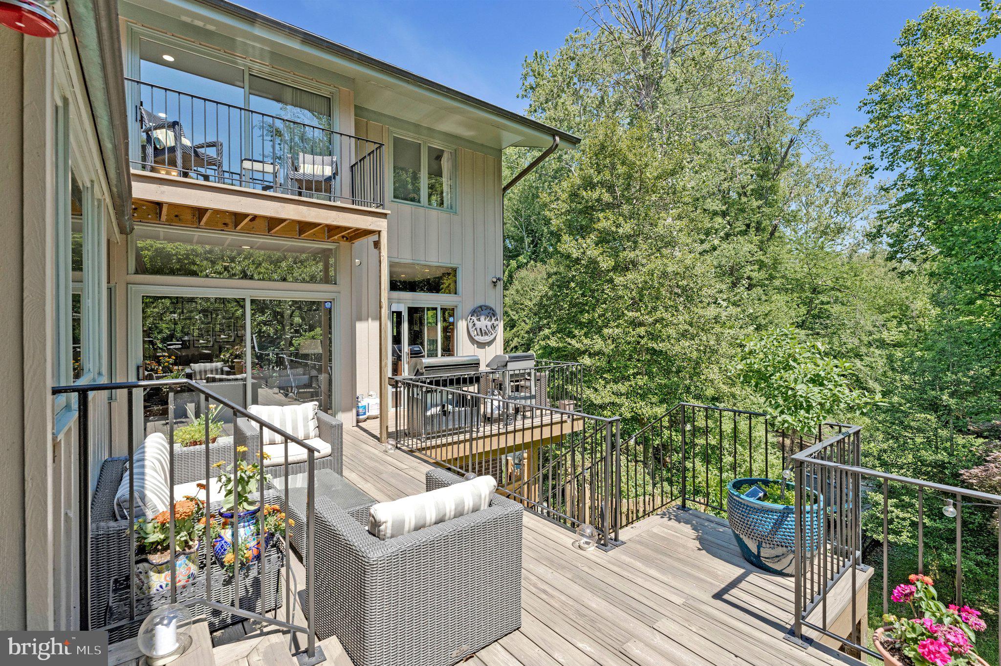 Tucked away in the highly sought-after Balmacara neighborhood, this stunning 5-bedroom, 4.5-bath contemporary residence impresses from the moment you enter its private gated courtyard. Filled with natural light from expansive windows throughout, the home seamlessly blends modern updates with timeless architectural charm, overlooking its own private forest.
The open-concept main living area is anchored by a striking stone-column fireplace that beautifully defines the space while maintaining an airy flow ideal for both everyday living and entertaining. At the heart of the home, the renovated kitchen features a large communal island, stainless steel appliances, and abundant prep and storage space. Just off the living area, a sophisticated office with floor-to-ceiling shelving opens directly onto the spacious rear deck, while an additional private den offers even more flexible living space and extensive built-in storage.
The luxurious owner’s suite serves as a peaceful retreat, complete with a private balcony overlooking the wooded backyard and a beautifully updated spa-inspired bath featuring split quartz dual vanities and generous cabinet storage. The suite’s versatile layout also provides the perfect opportunity for a sitting room or private office. Each secondary bedroom is filled with natural light and character, and the two carpeted bedrooms feature sand-in-place hardwood flooring underneath. Newly renovated full bathrooms further elevate the home’s thoughtful design. Main-level suite features an adjoining private bathroom with shower that includes grab bar and built-in, fold-down bench for adaptable seating, safety and comfort. 
Designed with both comfort and convenience in mind, the home also includes a wet bar, dedicated laundry room, and a charming sunroom surrounded by windows that showcase serene outdoor views year-round. Step outside to enjoy the expansive rear deck overlooking mature trees, a creek, and abundant wildlife — an ideal setting for relaxing or entertaining guests. Below, the in-ground pool and hot tub are surrounded by lush landscaping, creating a truly private outdoor oasis.
An additional parcel across the creek conveys with the property, offering a rare arboretum-like setting and enhanced privacy. The unfinished basement provides tremendous storage and future expansion potential, while built-in exterior-access storage is perfect for lawn and garden equipment
Ideally located inside the Beltway on a quiet cul-de-sac, just one stoplight from Maryland and the GW Parkway, within walking distance to Langley High School, and only minutes from downtown McLean, this exceptional property offers the perfect balance of privacy, nature, and convenience. Schedule your private tour today!