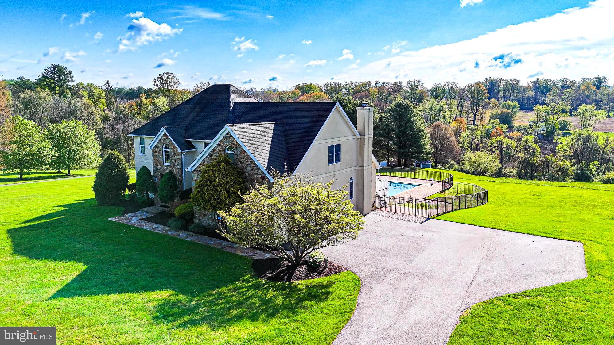 Tucked away on over 3 picturesque acres in the highly sought-after community of Mission Ridge, this rarely available custom home offers the perfect blend of privacy, comfort, and endless opportunity for entertaining and everyday living. Lovingly maintained by the original owners, this exceptional property was thoughtfully expanded in 2007 to create a one-of-a-kind lifestyle experience unlike anything else in Sparks. From the moment you arrive, the dramatic two-story foyer sets the tone for the impressive spaces throughout the home. Designed for both comfort and entertaining, the home features 5 spacious bedrooms, 4.5 bathrooms, two private offices, and expansive living areas filled with natural light. The stunning two-story main level family room is anchored by a classic brick wood-burning fireplace, creating a warm and inviting centerpiece for everyday living. The walk-out lower level offers additional recreation space complete with a custom brick wet bar ideal for hosting family and friends.
The true showpiece of the property is the incredible indoor recreation addition featuring an approximately 50 x 38 gymnasium perfect for basketball, pickleball, fitness, or year-round activities. Adjacent to the gym is a dedicated indoor area for a golf center, weight room, yoga studio, playroom or use your imagination to create a private retreat rarely found in residential homes. Movie nights become unforgettable in the custom theater room, which features tiered leather reclining seating for nine or more people, while the oversized walk-in closet adds another touch of luxury to the expansive primary suite.
Outdoor living is equally impressive with a fenced 40 x 20 concrete pool, large composite deck, brick paver patio, and sweeping scenic views in every direction. Whether entertaining guests or enjoying a quiet evening at home, every inch of this property was designed to maximize enjoyment of both indoor and outdoor spaces. Energy-efficient geothermal heating adds comfort and efficiency year-round.
Perfectly positioned near some of Baltimore County’s most treasured outdoor destinations, enjoy easy access to the NCR Trail — 21 miles of crushed-stone trails ideal for hiking, biking, horseback riding, and exploring alongside the beautiful Gunpowder Falls River, where tubing and outdoor adventures await. The historic 1916 Sparks State Bank, now transformed into a Nature Center, adds even more charm and character to this unique area. A truly rare offering combining resort-style amenities, privacy, scenic beauty, and neighborhood living — 10 Sparks Farm Road is a home designed to be experienced.