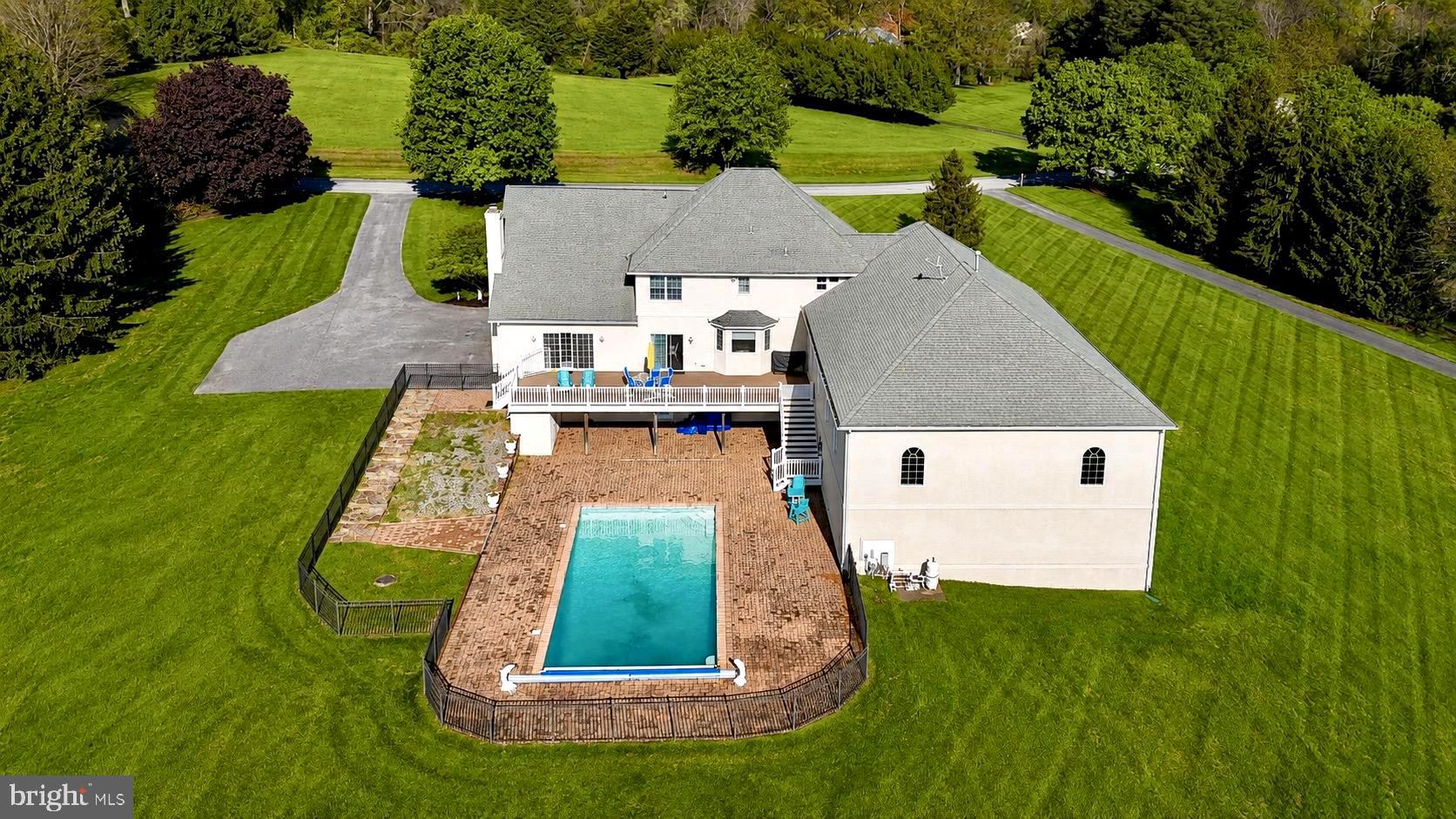 Tucked away on over 3 picturesque acres in the highly sought-after community of Mission Ridge, this rarely available custom home offers the perfect blend of privacy, comfort, and endless opportunity for entertaining and everyday living. Lovingly maintained by the original owners, this exceptional property was thoughtfully expanded in 2007 to create a one-of-a-kind lifestyle experience unlike anything else in Sparks. From the moment you arrive, the dramatic two-story foyer sets the tone for the impressive spaces throughout the home. Designed for both comfort and entertaining, the home features 5 spacious bedrooms, 4.5 bathrooms, two private offices, and expansive living areas filled with natural light. The stunning two-story main level family room is anchored by a classic brick wood-burning fireplace, creating a warm and inviting centerpiece for everyday living. The walk-out lower level offers additional recreation space complete with a custom brick wet bar ideal for hosting family and friends.
The true showpiece of the property is the incredible indoor recreation addition featuring an approximately 50 x 38 gymnasium perfect for basketball, pickleball, fitness, or year-round activities. Adjacent to the gym is a dedicated indoor area for a golf center, weight room, yoga studio, playroom or use your imagination to create a private retreat rarely found in residential homes. Movie nights become unforgettable in the custom theater room, which features tiered leather reclining seating for nine or more people, while the oversized walk-in closet adds another touch of luxury to the expansive primary suite.
Outdoor living is equally impressive with a fenced 40 x 20 concrete pool, large composite deck, brick paver patio, and sweeping scenic views in every direction. Whether entertaining guests or enjoying a quiet evening at home, every inch of this property was designed to maximize enjoyment of both indoor and outdoor spaces. Energy-efficient geothermal heating adds comfort and efficiency year-round.
Perfectly positioned near some of Baltimore County’s most treasured outdoor destinations, enjoy easy access to the NCR Trail — 21 miles of crushed-stone trails ideal for hiking, biking, horseback riding, and exploring alongside the beautiful Gunpowder Falls River, where tubing and outdoor adventures await. The historic 1916 Sparks State Bank, now transformed into a Nature Center, adds even more charm and character to this unique area. A truly rare offering combining resort-style amenities, privacy, scenic beauty, and neighborhood living — 10 Sparks Farm Road is a home designed to be experienced.