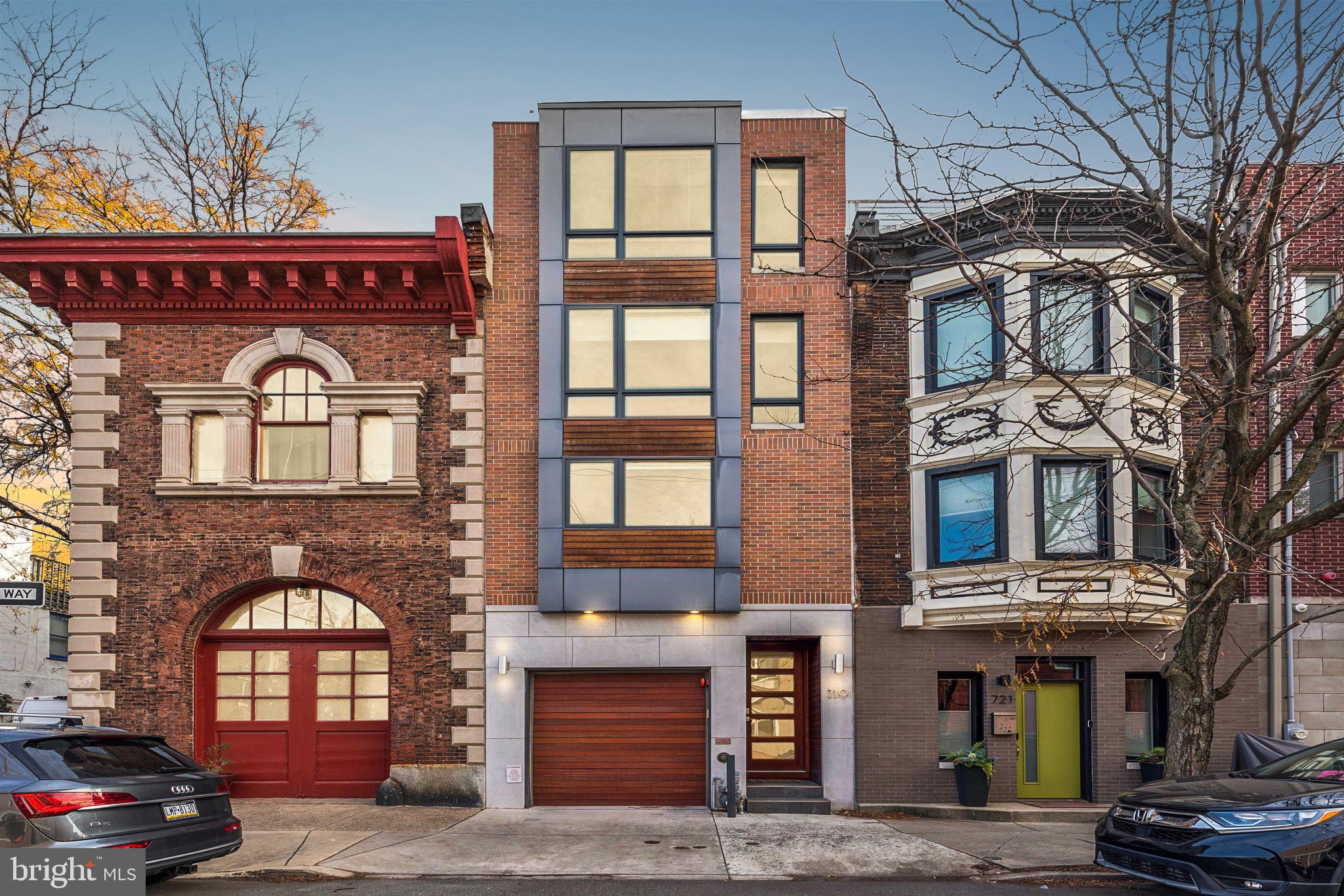 A rare contemporary masterpiece in the heart of Graduate Hospital, this four-story townhome—with GARAGE PARKING and ELEVATOR — delivers sophisticated design, exceptional craftsmanship, and 3 outdoor spaces. Built in 2017, this unique home pairs timeless materials with modern amenities, creating an effortless blend of luxury and comfort. A striking façade sets the tone, while an Azek-clad roof deck atop a TPO roof crowns the home with durability and style. Step through the vestibule with natural, unpolished stone tile and direct access to the one-car garage. Rich 7” wide-plank natural oak flooring flows throughout. The entry level hosts a serene guest suite or private home office with a custom travertine full bath and glass-enclosed shower. Sliding doors open to a tranquil stone-paved patio with a dreamy whirlpool spa. Ascend via the private elevator or custom stainless-steel and open-tread oak staircase to the main living level. Here, an elegant living room features a sleek gas fireplace, a ledge-stone accent wall, designer lighting, and double sliding glass doors to a charming deck with built-in gas line—perfect for grilling and al-fresco dining. A stylish bar area with Caesarstone Quartz countertops, wine refrigerator, and storage transitions seamlessly into the dining area and chef’s kitchen. Outfitted with Thermador stainless-steel appliances, rich Society Hill cabinetry, and matte Caesarstone waterfall counters and backsplash, the kitchen delivers beauty and performance. A chic powder room with slate accent wall and floating walnut vanity completes this level. The third floor offers two generous bedrooms with custom closets, a beautifully appointed hall bath with gray tumbled travertine in herringbone pattern, and a full laundry room with basin sink. The full fourth-floor primary suite is a private sanctuary, featuring two walk-in closets, an additional storage closet, and a dramatic west-facing floor-to-ceiling window wall. The spa-inspired primary bath boasts an oversized soaking tub, double vanity with natural stone accents, and a luxurious walk-in shower with body jets and stone bench. Continue upward to the expansive roof deck where stunning city views set the stage for unforgettable entertaining. A fully finished lower level with legal egress, wet bar, and beverage center provides exceptional flex space for a media room, fitness area, home office, or guest accommodations. Every detail exceeds expectation: digital front entry, Emtek hardware, video intercom, Honeywell security system, whole-house sprinkler system, and dual high-efficiency HVAC systems. Situated just south of South Street, this home offers unmatched walkability to premier dining, cafés, shops, and parks—with easy access to Rittenhouse Square, Fitler Square, CHOP, UPenn, and Drexel. TAX ABATEMENT through 2027, adding exceptional value to this extraordinary property.