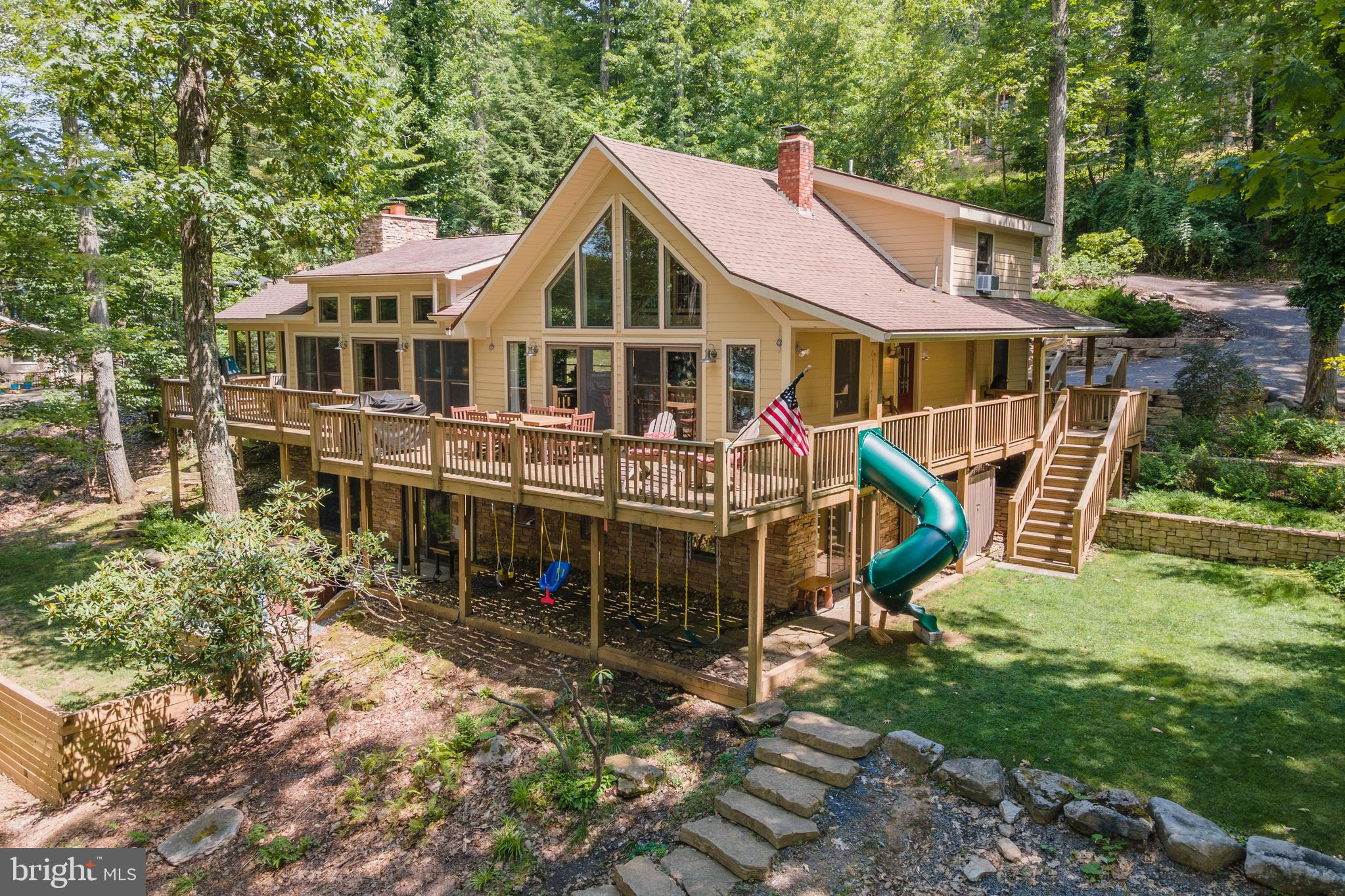 Elegant 5/6BR/4BA lakefront home with proven rental history (5 BRs for rental purposes), boasts a whopping 382 ft of waterfront, with a two slip dock. Ask listing agent for details of the dock arrangement. This home is NOT a member of the Edgewater HOA but is a member of the Edgewater Docks, LLC which gives it 2 boat slips. - 1.5 acres in total! Great lake views from most rooms, this centrally located beautiful home offers a contemporary lodge vibe - 3 stacked stone + wood burning fireplaces, beamed ceilings, wood floors and accents, a peaceful and quiet setting with just enough trees for privacy while maintaining excellent views of the water. Features include multiple master suites, custom tile bathrooms, eat-in kitchen, multiple living areas, attractive fixtures, and a unique design throughout. Magnificently maintained property boasts a wraparound lakefront deck, a bonus game room with fireplace and elaborate hardscaping designs while offering an otherwise low maintenance yard. Outdoor fire pit for relaxing evenings by the lake and a lower level game room only add to the value. Conveys mostly furnished. 2 paved parking areas, including a separate .10+ acre parcel with 30 ft waterfront (non-buildable). The home is NOT in Edgewater HOA, BUT it is a member of the Edgewater Docks LLC, for the convenience of the install and removal of the docks every year.  Deep water access and wide views of the lake with western exposure from the house and dock. Must see!