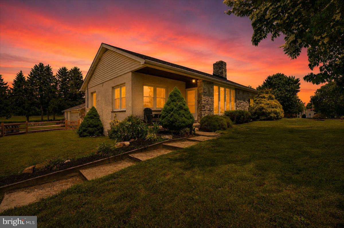 This updated one-story ranch home sits on a peaceful, tree-lined lot with large manicured lawns, mature trees, wooden fences, and open pastures. The property offers privacy and plenty of outdoor space in a quiet Downingtown setting.  Inside, the single-level home has been nicely refreshed with hardwood floors, high ceilings, and modern touches. The living area includes a large fireplace and big windows with views of the yard.  The kitchen offers dark wood cabinets, stainless steel appliances, a farmhouse sink, and marble-style tile floors. It connects to a spacious dining area. The home also has comfortable bedrooms, updated bathrooms, and a convenient laundry room.  The lower level is a major bonus. This large basement features high ceilings, concrete floors, and a massive garage in the back with multiple bays and overhead doors. The flexible space works great as a workshop, gym, storage area, or for future finishing.  350 Milford Road is a move-in-ready ranch home with modern updates, easy single-level living, and a large back garage. Ideal for comfortable country living near Downingtown.