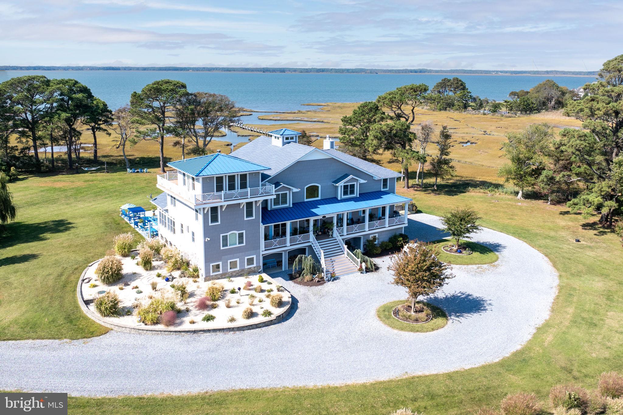 Welcome to 11209 Woodside Drive, an unparalleled waterfront masterpiece nestled on 8.7 private acres in South Point Farms, just minutes from Ocean City, MD and downtown Berlin, MD.  Offering stunning views of Newport Bay, this custom-built luxury home boasts 8,372 square feet of meticulously crafted living space.
Designed for both comfort and elegance, this 4-bedroom, 4-full and 2-half-bathroom estate features dramatic second-floor living and entertaining spaces, making it perfect for hosting guests—whether an intimate gathering or a grand celebration. The heart of the home is the chef’s kitchen, outfitted with top-of-the-line appliances and abundant storage space, while artistic custom features throughout elevate the home’s unique appeal.
The third-level primary suite provides a private retreat with a cozy fireplace, expansive closets, and sweeping water views. Outdoors, enjoy multiple porches, decks, and seating areas—ideal for watching spectacular sunsets or observing local wildlife. The 20x20 poolside 3-season porch invites year-round relaxation, and the private dock and nearby boat ramp offers direct access to 140 square miles of pristine, unspoiled waterways of Newport, Sinepuxent, and Chincoteague Bays, ideal for endless recreational water activities and enjoyment.
Additional highlights include an elevator servicing all three levels, a home gym, a climate-controlled dog room with exterior access, and a 5-car garage. This home is as functional as it is luxurious, with vast storage spaces, flexible living areas, and an abundance of indoor-outdoor living options.
Located just minutes from the acclaimed town of Berlin, Ocean City MD, and famous Assateague Island, this home offers a rare opportunity to experience the best of Eastern Shore coastal living. With world-class fishing, championship golf courses, and a variety of entertainment and dining options nearby, you’ll enjoy a lifestyle of unmatched convenience and serenity. Welcome to your dream waterfront retreat!