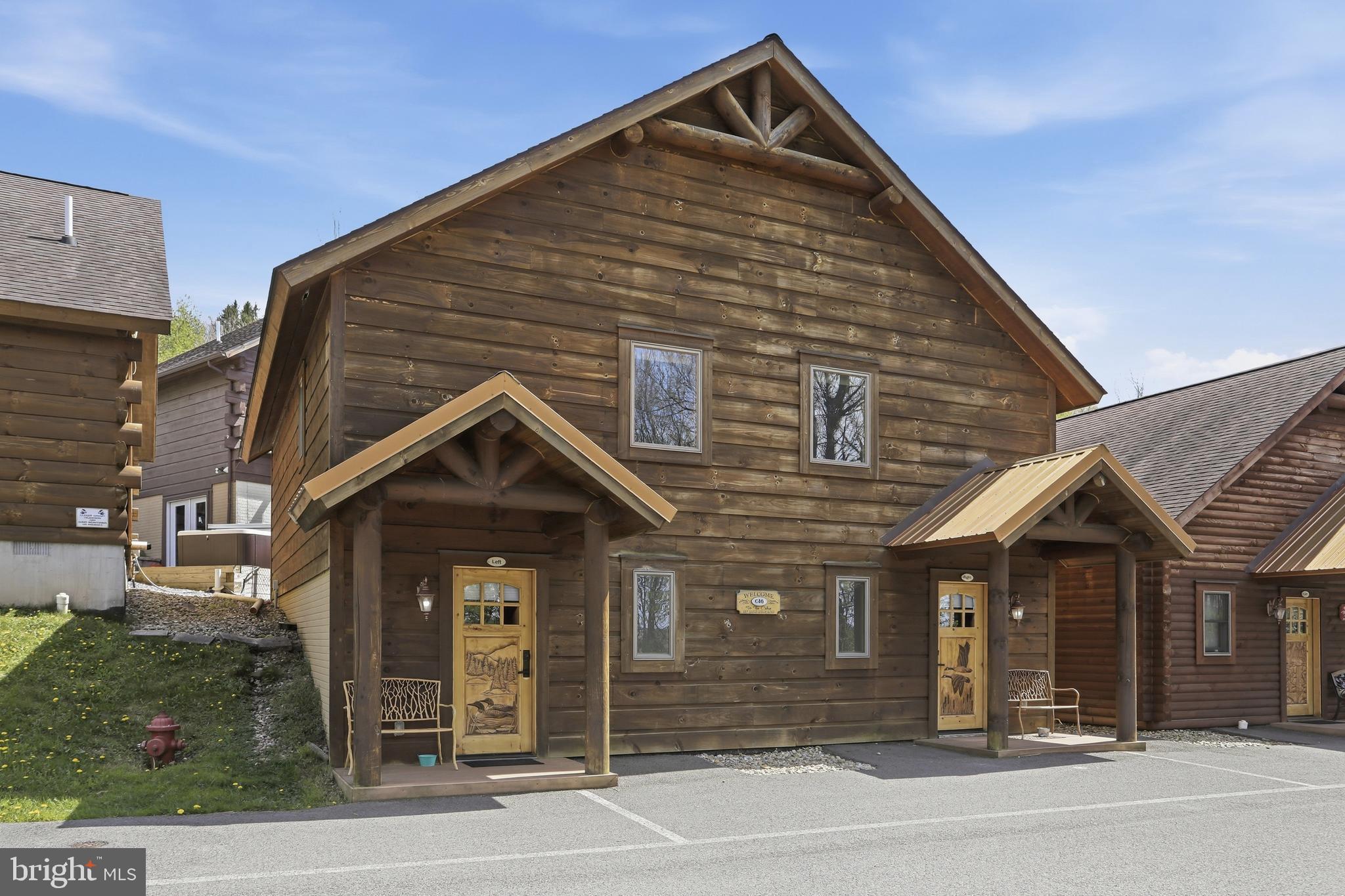 BOAT SLIPS! LAKE ACCESS & VIEWS! 4TH OF JULY FIREWORKS VIEWS! SKI SLOPE VIEWS! Cabin #46 at The Lodges of Sunset Village is a detached home offering two "lock off" units with a shared door between the units with 1472 square feet. Each side offers an efficiency-style layout on the main floor with two queen beds and a full bath, and a 2nd level with a separate queen bedroom and full bath.   This cabin includes two porches and a patio.

Rich in mountain character and charm, this log cabin features uniquely carved wood doors, beautiful beamed ceilings, warm wood walls, and inviting spaces that create an authentic lake and mountain retreat feel. Additional features include lake views, ski slope views, expansive decks and patios, upgraded finishes, open concept living, stacked stone gas fireplace, and open concept living.

Enjoy incredible views of Deep Creek Lake and Wisp, along with front row seats for seasonal beauty and memorable moments, including views of the annual July 4th fireworks. This property has a proven rental history, generating an average of  $66,320  in annual gross rental income creating an exciting opportunity for buyers seeking both personal enjoyment and investment potential.

Experience one of Deep Creek Lake’s newest ownership opportunities at The Lodges at Sunset Village. For the first time ever, fully furnished lake area cabins are being offered for individual ownership in a breathtaking community featuring incredible lake and Wisp ski slope views. Community amenities include lake access with 10 shared dock slips and an impressive 1,320 square foot waterfront dock area perfect for fishing, swimming, launching kayaks, relaxing by the water, and enjoying summer fun at the lake. Residents and guests also enjoy a lakeside gazebo, playground, fire pit, gathering areas, pet-friendly accommodations, abundant parking, and on-site professional management.

The monthly condo fee provides exceptional convenience, including most utilities, snow removal, trash service, and yard maintenance, for a low-maintenance ownership experience. Whether you're searching for a vacation retreat, income-producing investment, or both, The Lodges at Sunset Village offers a rare opportunity to own at Deep Creek Lake. Stop by our on-site Sales Center at The Lodges Gatehouse (23900 Garrett Highway) during open hours to learn more, explore ownership opportunities, and get your questions answered: Thursdays 2:00–6:00 PM, Fridays 1:00–5:00 PM, Saturdays 10:00 AM–5:00 PM, and Sundays 10:00 AM–2:00 PM or call today for details and your private showing!