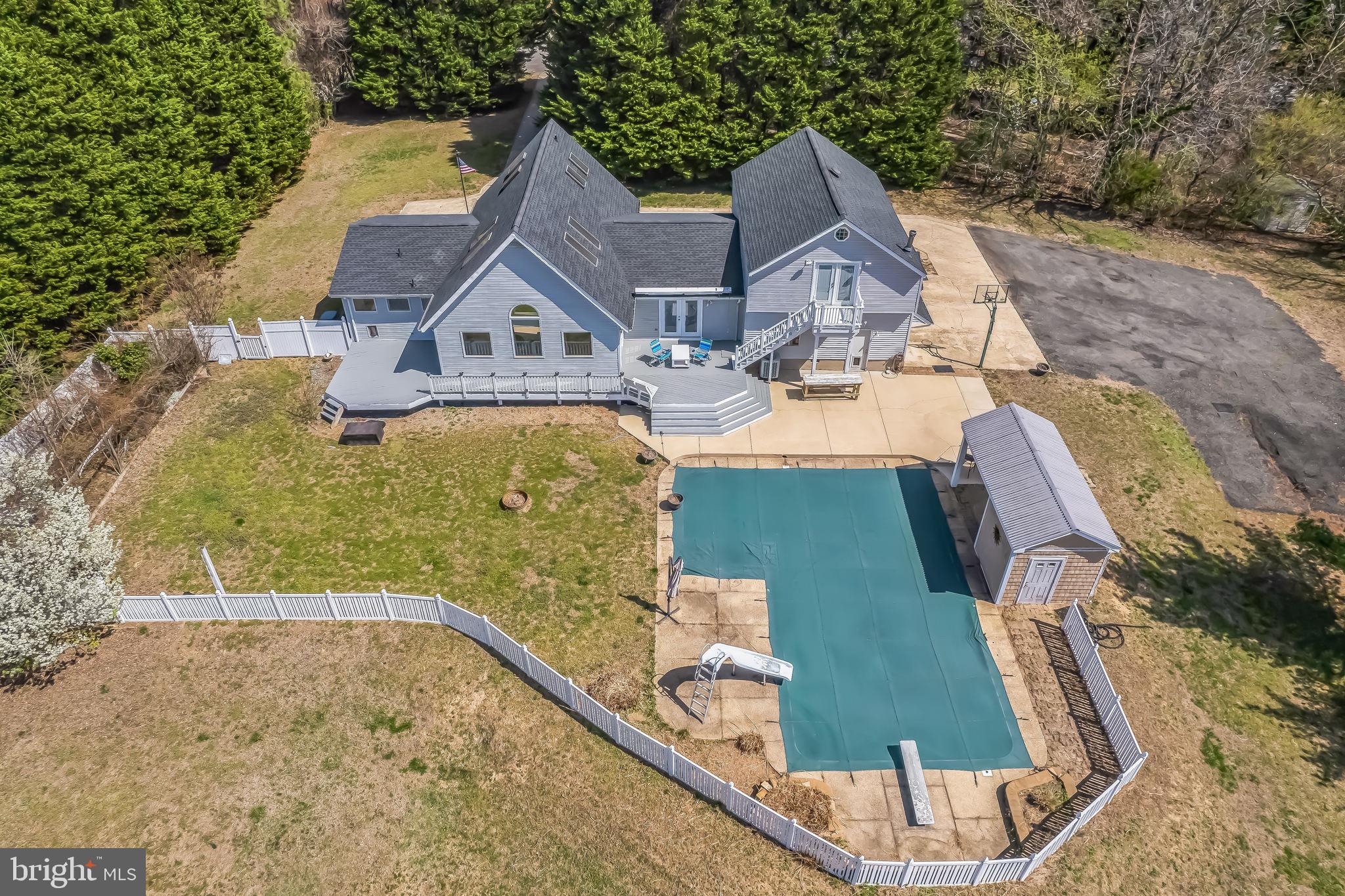 If you’re dreaming of the rural lifestyle but still want to be close to amenities such as restaurants, retail, and services, then THIS IS THE ONE!   This spacious, custom-built contemporary home rests on 5 private acres in the desirable Prince Frederick area and offers freedom from homeowner association (HOA) fees and restrictions!  The spacious home features 2,672 square feet of living space, including five generously sized bedrooms and two and a half bathrooms. The kitchen is particularly impressive, equipped with granite countertops, stainless steel appliances, a large island, 2-story ceiling, skylights, and ample space for dining. The main floor has two bedrooms, one of which offers a private full bathroom, a beautiful family room with lots of windows, a half-bath, laundry room, and kitchen/dining area. The remaining three bedrooms are located on the upper levels and include a jack-and-jill bathroom between the master bedroom and another bedroom that offers its own private entrance from the outside as well.  The 5th bedroom upstairs showcases vaulted ceilings and skylights, dormer closets, and is accessible via its own private staircase that is open to the 2-story kitchen. The 3-car garage provides plenty of storage space for vehicles and other items. The expansive side parking area will accommodate RVs, additional vehicles, and plenty of outdoor toys.  There is more than enough room to add barns, sheds, other outbuildings, and detached garages! The in-ground pool has depths ranging from 3 to 10 feet and includes a diving board and slide for lots of summer fun! The freshly painted rear deck extends along the length of the home and features an awning system that provides shade, and the patio areas provide additional space for outdoor entertaining. The absence of an HOA grants owners unlimited freedom to utilize the property as they desire. Always verify with the County but this property would be ideal for home-based businesses, livestock, horses, and other activities not normally permitted if there is an HOA.  Experience the rural feel of a country property while still being conveniently located near the Prince Frederick Town Center.  Within a reasonable commute to DC and Annapolis this property offers all the features of rural living combined with easy access to shopping and services!