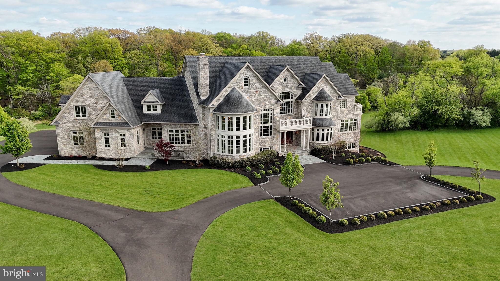 Perched at the pinnacle of an exclusive Upper Makefield Township enclave, this extraordinary residence by Zaveta Custom Homes offers over 10,000 square feet of refined finished living + an additional 3,500+ unfinished space (13,895 TOTAL), set on just about 13 acres of breathtaking, private grounds. Within the expansive acreage, 3 acres are available to build a second home on the property. Tucked away at the top of the neighborhood, the property delivers a rare blend of seclusion, grandeur, and timeless craftsmanship. A striking full-stone exterior sets the tone for what lies within three impeccably designed levels of luxurious living space where elegance meets modern comfort. The residence features five generously appointed bedrooms and six beautifully finished bathrooms, each curated with the finest materials and attention to detail. From the moment you enter, soaring ceilings, expansive windows, and exquisite millwork create an atmosphere of sophistication and light. The main level is designed for both grand entertaining and intimate living, with seamless flow between formal and informal spaces. A chef’s kitchen anchors the home, complemented by premium appliances, custom cabinetry, and thoughtfully designed gathering areas. The upper level offers a serene retreat, highlighted by a lavish primary suite with a spa-inspired bath and tranquil views of the surrounding landscape. Additional bedrooms provide comfort and privacy for family and guests alike. The fully finished lower level expands the home’s versatility, ideal for recreation, wellness, or entertainment, all while maintaining the same elevated standard of design. Outdoors, the 13-acre setting is nothing short of spectacular; rolling lawns, mature trees, and uninterrupted natural beauty create a private sanctuary just moments from the charm of Bucks County. Despite its serene, tucked-away setting, the property offers exceptional accessibility. Enjoy convenient proximity to New Jersey, seamless access to New York City, and easy connections to major highways providing direct routes north and south, as well as a straight shot east to the renowned Jersey Shore beaches. This is more than a home. It’s a statement of luxury, privacy, and enduring quality in one of the region’s most coveted locations. *Virtual Exterior Imagery Used*