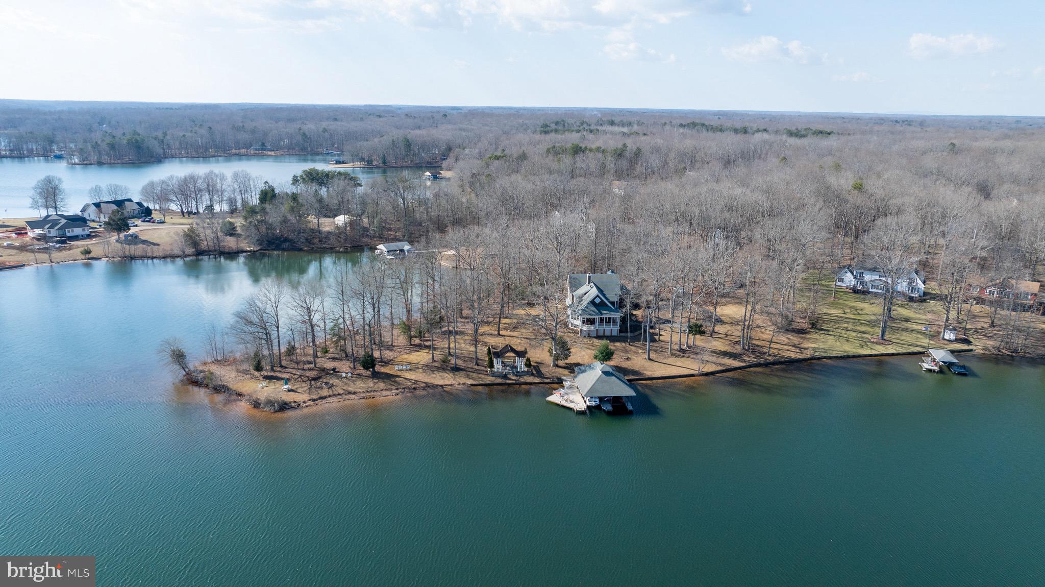 When you seek privacy, breathtaking lake views, exceptional waterfront amenities, and quality construction, The Peninsula at Lake Anna will be at the top of your list. Situated on the coveted Private Side of Lake Anna, this stunning 5,790-square-foot waterfront residence offers approximately 425 feet of pristine shoreline on a spectacular peninsula lot, creating panoramic water views in nearly every direction.

As you travel the long paved driveway, a sense of serenity and seclusion immediately takes hold. Nestled on approximately 1.5 acres, this remarkable property offers an unparalleled waterfront setting where spectacular sunrises, expansive water views, and the peaceful beauty of the lake become part of everyday life.

Inside, Southern charm meets timeless style. Natural light pours through expansive windows, framing breathtaking lake views from nearly every room. The thoughtfully designed floor plan provides ample space for both entertaining and everyday living, with multiple gathering areas that allow family and guests to come together while still enjoying private retreats throughout the home.

At the heart of the residence is an oversized kitchen with a generous walk-in pantry, offering abundant space for preparing meals, hosting celebrations, and creating lasting memories. Whether entertaining a crowd or enjoying a quiet evening at home, the home's seamless flow and waterfront backdrop create an extraordinary setting.

The spacious primary suite serves as a private sanctuary, featuring multiple closets and a well-appointed bath. Two additional upper-level bedrooms enjoy beautiful lake views, while the unique fourth bedroom is designed with a built-in raised sleeping platform and multiple adjoining sleeping areas, creating a wonderful space for children, grandchildren, guests, or multi-generational living.

The walkout lower level expands the home's versatility with a cozy den ideal for movie nights and gaming, a large flex room currently utilized as an office that could easily serve as an additional bedroom, and a spacious recreation area perfect for billiards, games, or entertaining. An unfinished nook offers the opportunity for a future kitchenette or bar area. Hobbyists and craftsmen will appreciate the dedicated two-room workshop with direct access to the attached two-car garage.

The outdoor living experience is equally impressive. Expansive decks and lakeside gathering areas invite you to relax and enjoy the magnificent waterfront setting. At the shoreline, a truly exceptional boathouse serves as the centerpiece of the property's waterfront lifestyle. Featuring two boat slips with lifts, a lakeside tiki bar, drop-down television, private storage room, and an expansive sun deck above, this waterfront retreat is designed for both relaxation and entertaining. Whether hosting family and friends, watching the big game after a day on the water, or enjoying a sunset cocktail overlooking the lake, this remarkable space elevates lake living to an entirely new level.

Additional features include an automated air injection oxidizing filtration system, whole-house particulate filtration system, and an active radon mitigation system already in place.

Rarely does a property combine such exceptional waterfront, privacy, entertaining spaces, and family-friendly accommodations in one offering. The Peninsula at Lake Anna presents a unique opportunity to create lasting memories in one of the lake's most extraordinary waterfront settings.