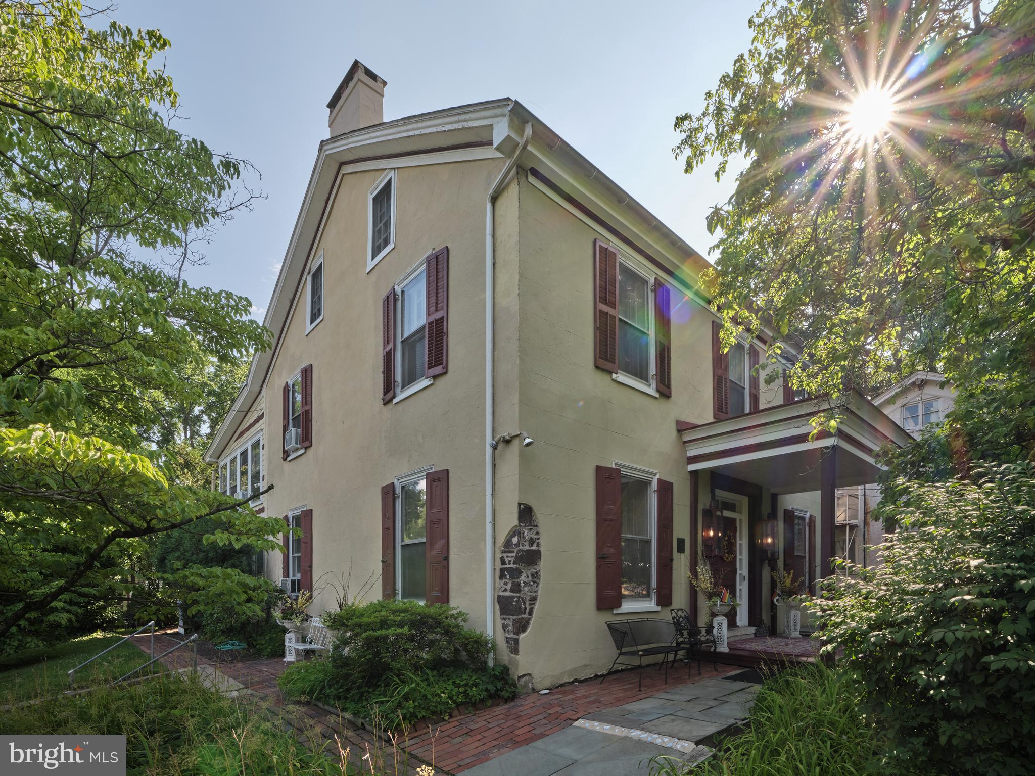 In the heart of New Hope’s historic district is the Umpleby House, a Classic Revival plaster over stone manor house built in 1833 and a delightful one bedroom, one bath two story carriage house on the same property. Currently a luxury Bed and Breakfast, this approximately 4800 square foot manor could also make a wonderful home for the discerning buyer who desires the artisan craftsmanship of an historic property along with the amenities of the twenty-first century, and a separate building for guests or in-laws and all on a large, landscaped lot in one of the best locations in New Hope. Named as one of “America’s Favorite Towns” by Travel and Leisure magazine, New Hope Pennsylvania is a beautiful village with a long and storied history. Located just an hour from Philadelphia, 90 minutes to NYC and half an hour from Princeton, New Hope is a wonderful location for those that like the convenience of being able to walk into a bustling hub of shopping, restaurants and galleries but retain the relaxing feel of village life. The Umpleby House, named after William Umpleby, a local mill owner, is an elegantly refined building built on a pre-war foundation and served as headquarters for General Washington’s Army for six years. A Victorian-era addition was added to the rear in the late 1880s by owner Colonel Buckley. The current owners purchased and renovated Umpleby House in 1985, converting it to the 8 suite upscale, luxury inn that it is now.  They also added the fanciful three-tier Victorian porches in 2001. A classic front entry provides a visual memory of the buildings original use as a single family home. A long center hall and grand staircase is currently flanked by a beautiful guest suite to the right and a formal living room with fireplace on the left. All of the historic craftmanship is evident, 9’ ceilings, deep handcrafted moldings, random width hardwood floors, refitted antique lighting fixtures, tall double hung windows with deep window wells, the historic detail that will be retained in the rediscovery of the homes original purpose. Main floor guest suites can become living and dining rooms again. The suites on the second floor can become luxurious bedroom suites, some with private entrances and balconies, freestanding gas or electric fireplaces and the third floor could become a fabulous primary bedroom suite. A 550SF caretaker’s apartment in the basement might be the perfect place for a nanny, au pair or recreation room. The large country kitchen is ready for all of the future celebrations that will take place here. If multi-generational use is needed what better place than the Carriage House? Just a few steps away, overlooking the lush lawn and landscaping, the two story Carriage House features a main floor living area with woodstove and a full bath and a second floor bedroom with large covered porch. One can easily imagine an expanded kitchen area so that Mom and Dad can have privacy but still be close by. An attractive two car detached barn/garage completes the property. There are precious few opportunities in New Hope to have this kind of history, space, amenities, large lot, plenty of parking and all in the best location. The Umpleby House is waiting for the vision of its next stewards to take it from its current life as an elegant inn to a future as a single family home.