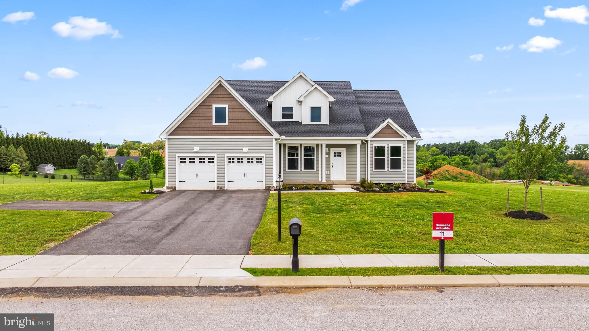 Welcome home to 347 Steeple View Dr in Hanover PA! This newly constructed craftsman-style home offers plenty of open living space on just over 2 acres with panoramic country views and no HOA. Located near the Maryland line, the property provides convenient access to Hanover, York and surrounding Maryland commuter routes including Route 94 and Route 30. The main level features a grand 2 story great room with vaulted ceilings, an exposed wood beam and a gas fireplace, flowing seamlessly into the dining area and kitchen. The kitchen is designed with quartz countertops, a large island, farmhouse sink, champagne hardware, stainless steel appliances and an oversized walk-in pantry. Sliding glass doors off the dining area overlook the backyard and open countryside. The first floor primary suite offers large windows, cathedral ceilings, dual walk-in closets and a luxurious ensuite bath featuring a double vanity, soaking tub, fully tiled glass shower and private water closet. The first floor also includes a flexible office or formal dining space, half bath and mudroom entry from the attached two-car garage. Upstairs are three generously sized bedrooms and a shared full bath. The unfinished basement spans the full footprint of the home and includes rough-in plumbing and walk-up sliding door access, offering exceptional potential for future living space, recreation areas or additional storage. A rare combination of modern construction, acreage, and custom finishes in a highly desirable and convenient commuter location. Schedule your private tour today! Photos shown are of a model home or similar floor plan and are for illustrative purposes only. Actual home, finishes, features, and selections may vary. Photos may include optional upgrades not included in the purchase price.
