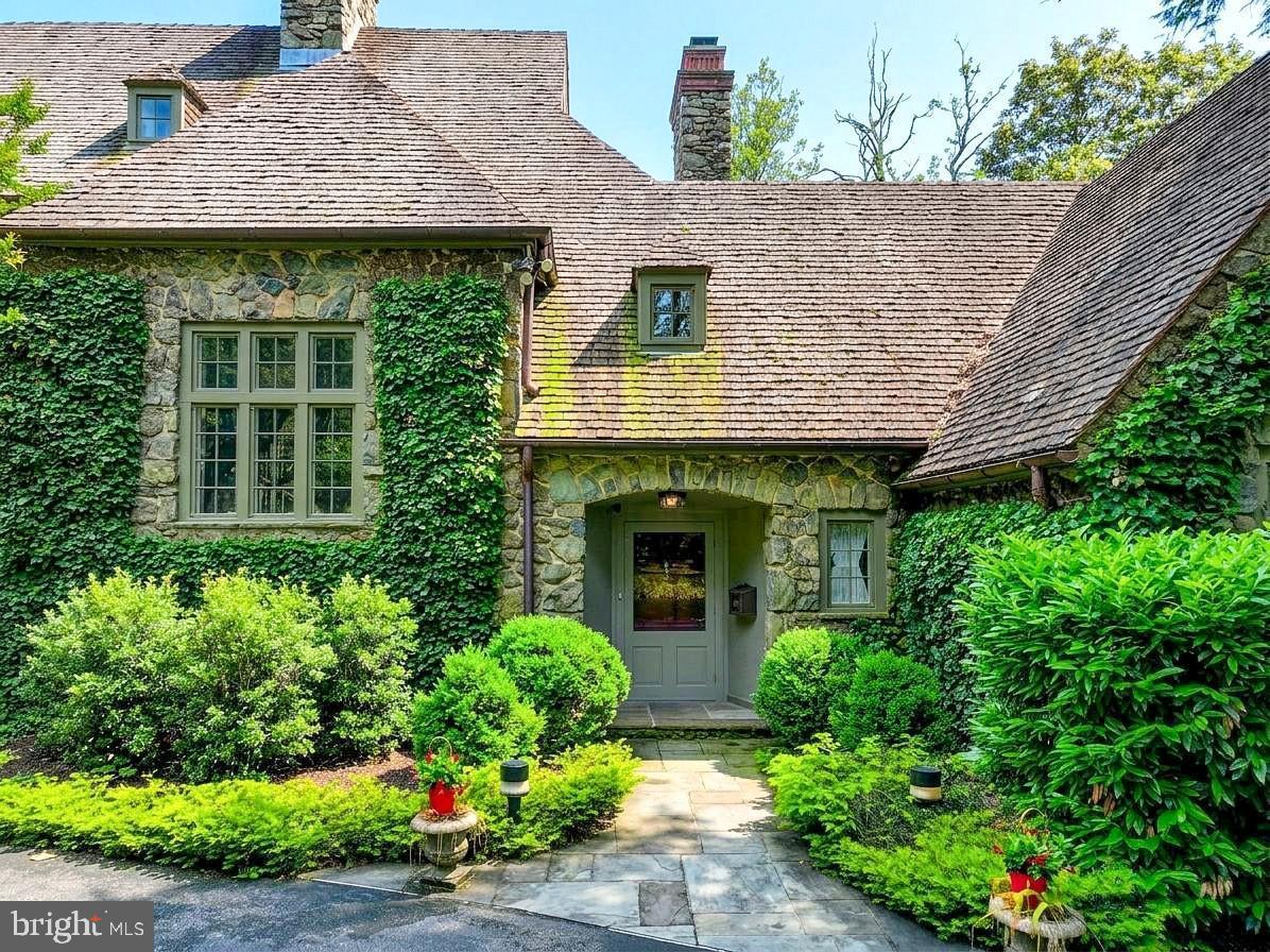 Welcome to this distinguished Baltimore estate, a residence of exceptional grace and grandeur designed by Palmer and Lamdin, as it awaits its next chapter. 102 Cotswold Road is an architectural treasure—a 1932 English Tudor Estate, set on 2.5 private acres in the highly desirable Homeland /Roland Park corridor. This nearly 9,000-square-foot stone manor offers an unmatched blend of historic charm, modern functionality, and estate-caliber grounds located in one of Baltimore’s most storied neighborhoods of Homeland.  The home’s exterior evokes old-world elegance, with its hand-hewn stonework, layered tile roof, and leaded glass windows. A long, private drive leads to the front entrance, framed by mature trees and lush, manicured landscaping. Step inside to discover interiors that have been lovingly maintained and thoughtfully updated. Original intricate millwork, arched doorways, ironwork details, and 9’ ceilings reflect the craftsmanship of a bygone era.  Designed for both gracious entertaining and comfortable daily living, the floor plan offers expansive rooms, a chef’s kitchen, a music room, cozy studies, sun-filled solariums, and intimate family spaces. The first level is also home to the grand primary suite, inclusive of dual renovated marble bathrooms with heated floors, multiple custom closets, and a gorgeous dressing room. Upstairs, multiple bedroom suites with renovated marble baths provide privacy and flexibility. The second level also offers an original sleeping porch that has been enclosed to house a bonus office room, plus a hallway office with built-in bookcases, and breathtaking views from every window. The third floor houses an expansive fanciful children’s playroom, full bathroom, and wonderful storage areas.  Outdoors, the estate’s sweeping lawns, stone terraces, and park-like gardens create a private sanctuary right in the heart of town. Perfectly positioned near Baltimore’s top private schools, cultural institutions, restaurants and boutique shopping, this one-of-a-kind property is truly a rare offering—ideal for the discerning buyer seeking heritage, grandeur, space, and tranquility.