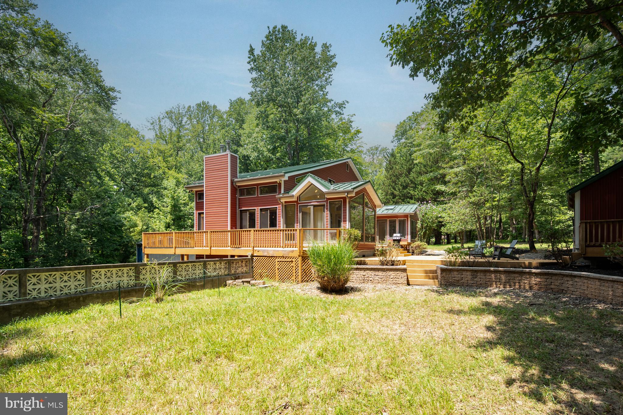 Escape to a private sanctuary where custom craftsmanship meets the serenity of nature. Set on over five secluded acres bordered by mature trees and lush landscaping, this three-story estate offers a lifestyle of quiet luxury just moments from the equestrian trails and scenic beauty of Patuxent River Park.
The heart of the home is a stunning main living room, where vaulted wood ceilings, wood floors, and a floor-to-ceiling stone fireplace create an atmosphere of rustic elegance. The kitchen is a chef’s dream, featuring a massive central island perfect for gathering and meal prep. The eat-in kitchen has amazing natural light and a propane fireplace. Transition easily through the formal dining room into the sunroom, another vaulted space bathed in natural light, which opens directly to one of the many decks and lush surroundings. The main level also boasts a bedroom, half bathroom, large laundry room, and extensive storage.
The upper level is designed for relaxation. Retreat to the primary suite, a true oasis featuring a private balcony, two bright skylights, and a spa-like ensuite bathroom. The bathroom offers a two-person jetted tub set under its own skylight for the ultimate evening wind-down. Another bedroom-with its own private balcony, a full bathroom, and a loft rounds out the upper level.
The walkout basement completes the interior with even more features. You will find another living room with a fireplace, wet bar, and a full bathroom. In addition, there is a large storage and utility room and access to the attached two-car garage.
Outdoor living is equally impressive. This home boasts multiple decks connecting most rooms to the outdoors. There is a generous fully wired garden shed with a garage door and overhead storage along with a hobbyist's dream workshop, wired for 240v 60amp welder and 240v 5hp compressor.
This home has been meticulously cared for, it has a newer standing seam steel roof and Dutchlap Steel Siding, a whole-house water filtration system, hardwood floors and ceramic tile throughout, and is wired for surround home theater, among many other upgraded amenities.
With four spacious bedrooms and three and a half baths, the home provides ample room for everyone. Whether you’re exploring the nearby park trails or hosting a summer gathering on the deck, this property offers a rare blend of privacy, scale, and custom detail.