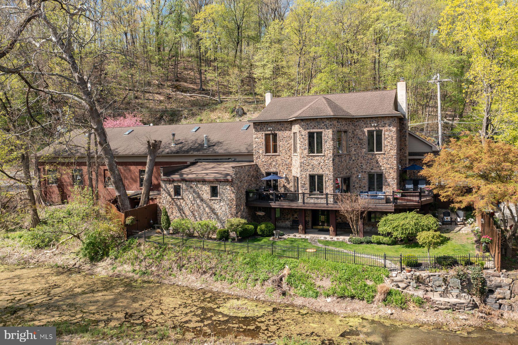Waterfront, Delaware River Views. For those who have always wanted waterfront and water views, this property offers so much for the ultimate convenience and comfortable living. This 5,000+ sq ft home provides easy access to a very well-designed and ample commercial space one could use as an art studio, woodworking shop, car collection, food catering, or anything else one can want right next door. Plus room for an apartment. The property has been used as a used car dealership, and the current owners have maintained the commercial status, allowing potential buyers unlimited opportunities for at-home business. The home sits proudly on the historic Delaware River Towpath with views of the Delaware River from three sides of the house.  Sit on your back deck while dining under the sun and watching eagles hunt for their dinner. The current owners designed and constructed this home with great care and thoughtfulness, adding many spectacular handcrafted antiquities. The large open kitchen boasts a 24-foot antique oak bar transplanted from a historic Allentown Hotel bar. The solid carved oak bar is a must-see piece with granite countertops, stainless steel appliances, and a pantry.
The first floor showcases gleaming hardwood floors made from Asian Walnut Acacia which travels through the open dining and living room  and kitchen with floor-to-ceiling windows looking out over the river attached to a wraparound cedar and Trex deck overlooking the canal, towpath, and River. The ceiling heights on the first and second floors are 10 feet high, making the space feel big and light. Throughout the house, the owners have lovingly curated antique wall sconces and ceiling lights. The oversized family room has a Kona Pecan hardwood floor with an updated 1/2 bathroom attached. The foyer, which connects the house to the commercial space, has so many exceptional hand-picked antiquities, including hand-carved Griffin church pews from an 1800s church with stained glass doors and windows with original brass hinges and hardware. The second floor has three bedrooms, two full baths, and a beautifully decorated and designed laundry room. The laundry room features a granite-topped folding station, a gift wrapping area, and a lovely built-in farm sink. The main guest room overlooks the Delaware River. The master suite is impressively sized with  a marble-tiled sitting room with a hand-carved antique oak mantle over a decorative fireplace with oversized windows overlooking the river. One of the built in dressers is a huge oak closet from the 1890s. Plus there is a spectacular solid Oak door that is 3 in" thick which leads out to a lower roof that is begging for a deck. The master has three walk-in closets for him and her. And wait until you see the master bath with a double shower, antique doors, and more stained glass. Much of the stained glass in the house was done by a world-renowned stained glass artist, Richard Smith.  The master suite has a second sitting area with skylights. Off the master are two additional rooms used as a gym and a hobby room. The attic space on the same floor is perfect for storage or a future apartment with access to a separate entrance. The lower level of the home offers another family room and a mudroom with a laundry that leads out to a very special private and quiet yard overlooking the towpath, canal and river. There are stone steps leading to the canal for easy access to your canoe or kayak. Bring your dreams of working at home with so many opportunities for your business endeavors.
