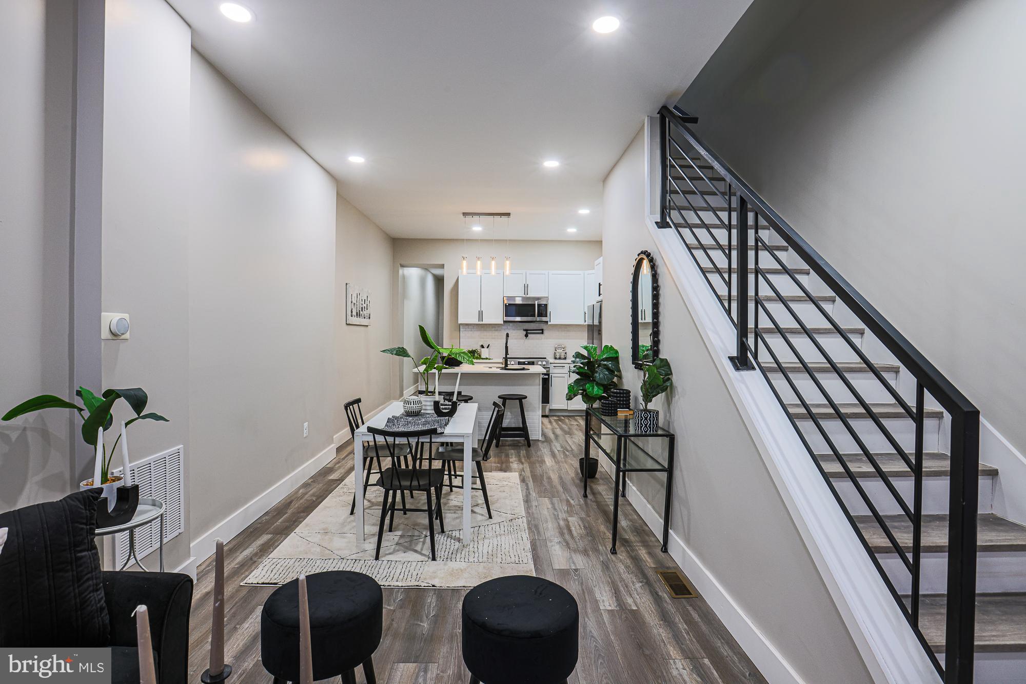 Welcome to this fully renovated porch-front brick rowhome offering modern finishes, open living, and flexible space throughout. Step inside to tall ceilings, recessed lighting, and new LVP flooring that flows seamlessly throughout the home. The open floor plan creates the perfect setting for entertaining in the living room and hosting dinners in the dining area. The spacious kitchen is a standout, featuring abundant cabinetry, ample prep space, quartz countertops, stainless steel appliances, a tile backsplash, and an island with stool seating for quick bites or casual gatherings. A main-level bedroom and powder room add flexibility and convenience. Upstairs, the light-filled primary bedroom boasts a beautiful bay window and a private ensuite bathroom with a tile-surround tub/shower combo. Two additional bedrooms and a full hallway bathroom with a tub/shower combo complete the second level. Laundry is conveniently located on this floor. The unfinished lower level offers excellent storage or the opportunity to add additional living space. Outside, enjoy a rear patio that can also be used for private parking. Conveniently located near Route 40, Reisterstown Road, Druid Hill Park and Mondawmin Mall, this move-in-ready home is a must-see. Schedule your showing today!