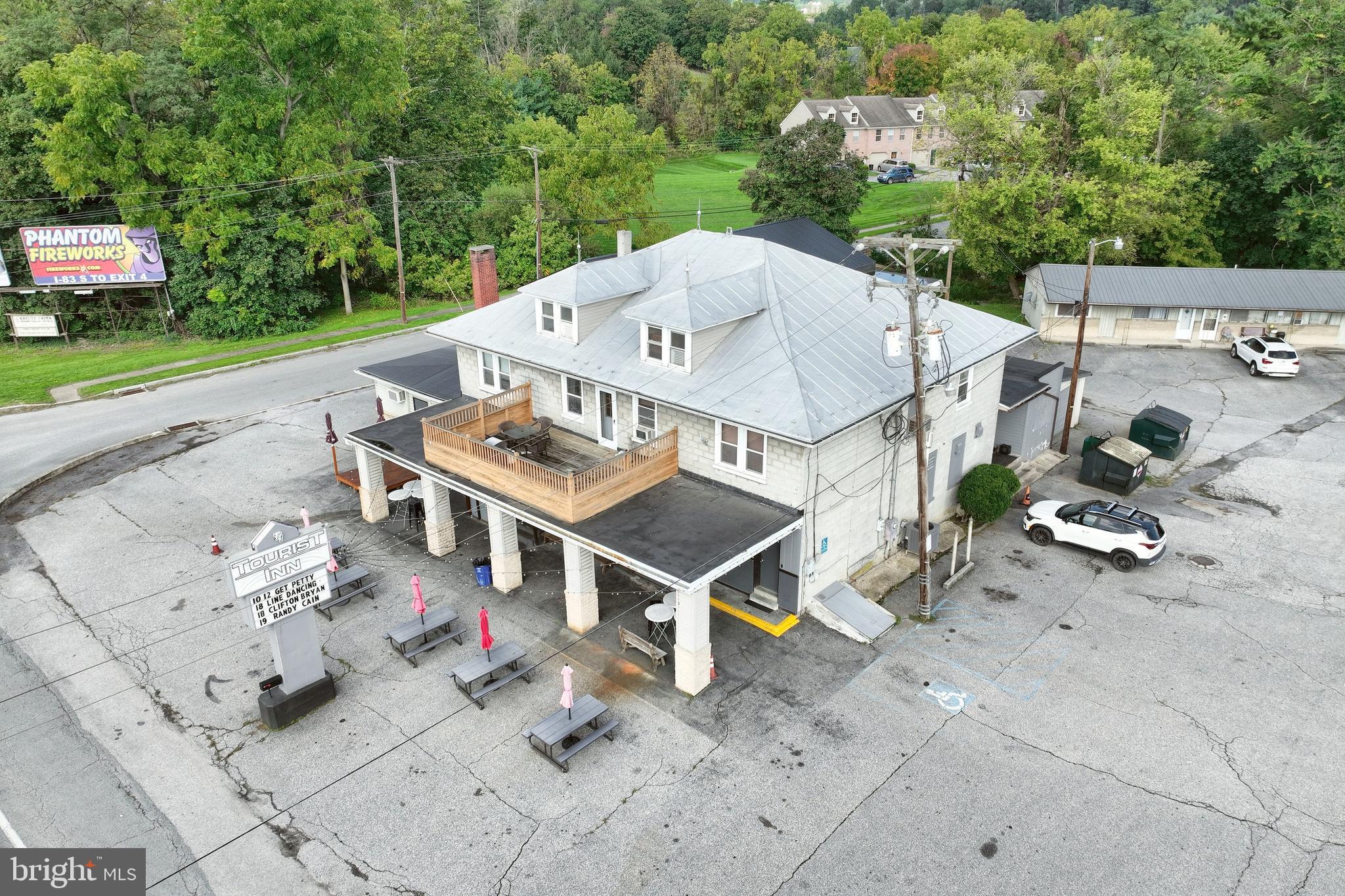 Here’s your chance to own a piece of York County history with The Tourist Inn, a renowned bar, restaurant, & entertainment venue that has been a landmark in Hellam for decades. Situated at the prime corner of Lincoln Highway and Kreutz Creek Rd, just moments from Route 30, this location offers high visibility and heavy traffic—making it an ideal stop for both locals & travelers. This sale includes the thriving business, real estate, 7 motel rooms, 3-bedroom apartment above the establishment, an "R" liquor license, all inventory (wine, beer, spirits), and fully-owned equipment. The Tourist Inn welcomes guests with a lg. parking lot easily accommodating 75 vehicles, with capacity for up to 125 during events. The outdoor area features picnic tables, hightops under the lg. porch, outdoor bar, small stage for performances, & a relaxed atmosphere. Step inside to one of the largest bars in York County—a stunning 28+ seat wraparound wooden bar. In addition to bar seating, the room offers hightops and engaging activities like darts and skill games. On busy nights, guests can enjoy additional seating at a bar-top counter that separates the main bar from the pool room. The adjoining pool room is a highlight of the bar scene, with 2 regulation-size coin-operated pool tables regularly in use. The room’s cozy atmosphere is enhanced by a fireplace, which may be original. Additional seating for 20+ guests lines the room’s walls, creating an inviting space for billiard enthusiasts and casual visitors alike. For larger events, "The Back Room" offers an expansive, hidden gem of a space. Equipped with a full stage, it hosts live performances & can comfortably hold over 125 guests. This room has its own fully-stocked bar, private bathrooms, & separate entrance—perfect for private events or ticketed performances. A band room, covered in graffiti & signatures of famous performers, adds an authentic backstage vibe to the venue. The kitchen serves a classic American bar menu of wings, burgers, & other crowd favorites. It’s equipped with an oven, grill, deep fryers, a sandwich station, & a prep area, efficiently catering to the crowds drawn to this popular spot. Behind the scenes, there’s ample storage, including a dry storage room, dish room, walk-in freezer & refrigerator & an office for management. A large basement houses the kegs, soda systems, & utilities, & add’l storage. Above the establishment is a 3-bedroom apartment with a spacious balcony over the outdoor bar area. Also, there are 7 rental units—4 one-bedroom apts. and 3 single rooms. Four of the 7 units are currently rented long-term, along with the main apt. The rental potential for these units is significant, with market rates of $1,000/month for 1-bedrooms, $750/month for single rooms, & $1,300/month for the 3-bedroom apartment. Fully rented, this could bring in an additional $90,600 annually. This property is a rare opportunity to acquire a successful business, prime real estate, and a piece of the local heritage. Don't miss out on this iconic York County landmark!