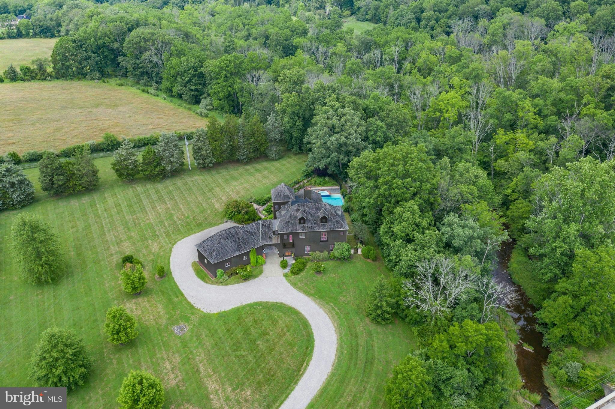 Renovated in 2021 and set on 3 private acres with views over pristine Cooks Creek, this stunning villa is a rare blend of 19th century touches & outstanding modern luxuries. European architecture is married to the classic PA environs through clever design & construction. A cedar shake roof, textured stucco exterior & antique c.1910 French doors provide focal points. At every turn there is meticulous attention given to the patina of the plastered walls, antique wood flooring & placement of elegant windows, arches, & doorways.

The breathtaking great room has radiant-heated limestone floors, a grand ceiling height w/century old beams, a fireplace with 1820’s lintel, antique doors from New Orleans, multiple arched doorways & opens to a patio perched above Cooks creek. The kitchen is a cook’s dream, equipped w/ an AGA range, gourmet appliances, limestone counters, farmhouse sink, separate prep kitchen & fireplace. The luxurious primary suite has a fireplace, 3 balconies, a jetted tub positioned in a windowed alcove, & bath with heated floor & steam shower. 2 en-suite BRs w/balconies & a separate 2021 office complete the 2nd floor, while a BR, family room & full bath are on the 3rd floor. The heated 3-car garage is connected by a porte cochere.

The gorgeous pool, spa & terrace are spectacular vantage points for entertaining, with Cooks Creek providing an incomparable backdrop. Adjacent preserved lands ensure that this breathtaking beauty will always remain.