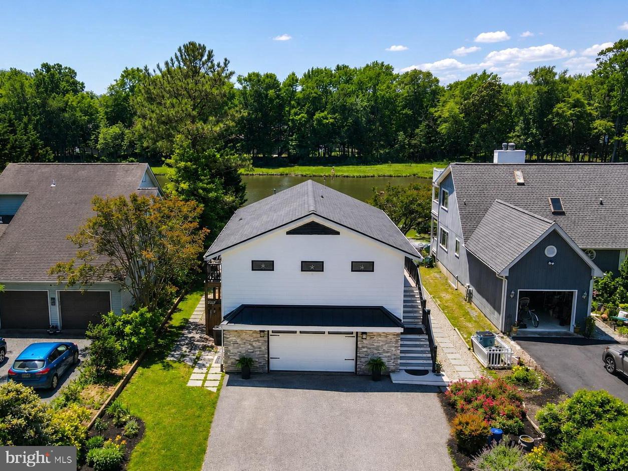 Nestled along the water in Ocean Pines, 44 Boston Drive is a beautifully renovated waterfront retreat offering the perfect blend of luxury, comfort, and outdoor living. Extensively remodeled in 2019, this stunning home was thoughtfully redesigned with raised ceilings, an open-concept floor plan, new siding and windows, and upscale finishes throughout. Step inside and immediately appreciate the light-filled great room featuring luxury vinyl plank flooring, a striking stone electric fireplace with space for a large-screen TV, and a wall of sliders that frame peaceful water views. The gourmet kitchen is truly the centerpiece of the home, boasting upgraded appliances, a large center island with granite countertops and dramatic waterfall edges, plus a convenient pantry for extra storage. This home offers 2 spacious bedrooms and 2.5 beautifully updated baths, each showcasing custom tile work, vessel sink, designer paint selections, and elegant finishes. The primary suite provides a relaxing retreat with a gorgeous private bath and generous closet space. Outdoor living is where this property truly shines. Step through the expansive sliders onto the huge wraparound deck with sleek glass panels designed to maximize the breathtaking water views and surrounding nature. A newer pier and dock make waterfront living effortless, whether you enjoy boating, kayaking, or simply soaking in the scenery. One of the most unique features of this property is the oversized backyard — a rare find in this section of Ocean Pines — offering endless possibilities for entertaining, family gatherings, cookouts, and lively cornhole tournaments. Beneath the deck, you’ll find an additional covered outdoor living area perfect for creating your own private patio retreat, complete with your own hot tub to enjoy year-round. Additional highlights include mature landscaping and a spacious 2-car garage ideal for storage of all your beach and boating essentials. This exceptional waterfront home has been meticulously updated and designed for easy coastal living. A must-see property that truly delivers the Ocean Pines lifestyle — you won’t be disappointed.