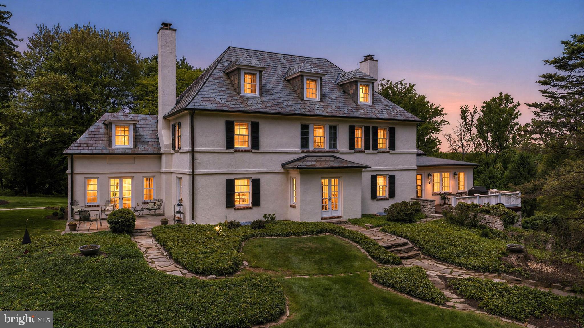 Four Winds, a venerable Ruxton estate house set amidst beautiful landscaped 2.4 acres including fine old growth and specimen trees. Solidly built with stucco over block construction and Vermont Semi-Weathering Green slate roof. Warm and gracious with bright sun-filled rooms and gleaming hardwood flooring throughout. An elegant classic staircase anchors the entrance foyer with the living room, dining room and library radiating from this space. Both the balanced living room and formal dining room feature woodburning fireplaces with fine colonial mantels. A cozy sunroom with 3 walls of windows and 2 sets of French doors can be found off the living room. Perfect as an office or to enjoy as a quiet retreat, the library features built-in bookcases and French doors to the gardens. There is an incredibly functional gourmet kitchen and butler's pantry with a large breakfast area, granite and solid-surface counters, top-of-the-line appliances and open flow to the family room with 2 walls of windows and access to the elevated deck, perfect for al-fresco dining or morning coffee.  The main staircase features an oversized window on the upper landing and wraparound railing overlook to the foyer below. An expansive primary suite with woodburning fireplace, marble spa bath and walk-in closets shares the 2nd level with 3 additional bedrooms and 2 baths. The open back staircase gives access to the 3rd level with its 2 bedrooms, hall bath, walk-in cedar closet as well as ample storage. A recreation room, laundry room/workshop and 2 car garage can be found in the lower level. A bluestone patio, mahogany deck and a secluded in-ground pool, all set amidst lush landscaping.