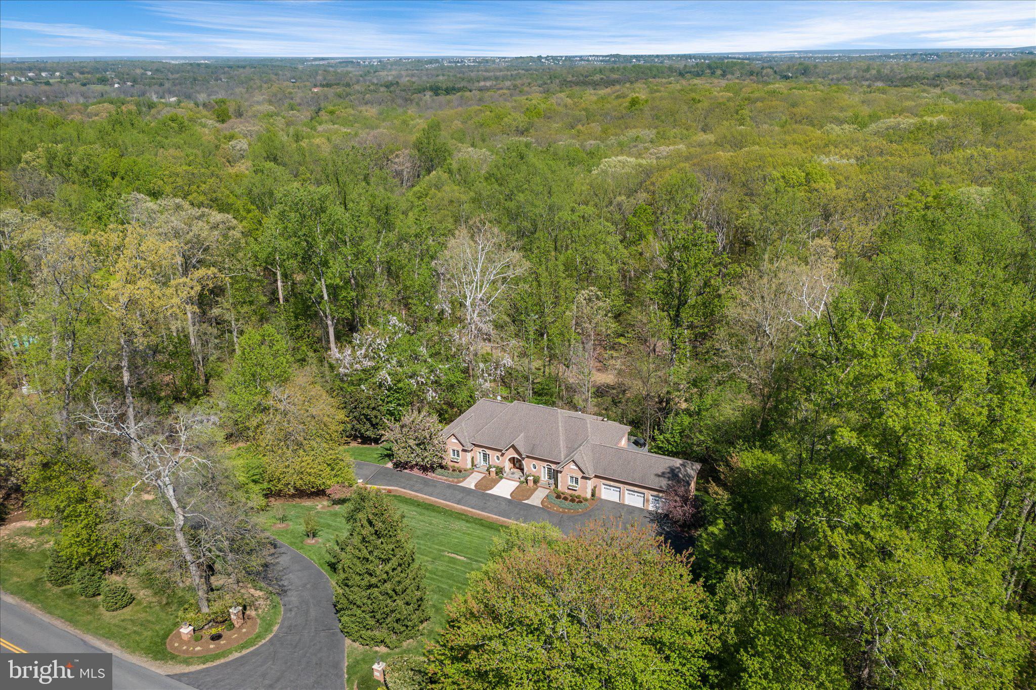 A home of quiet distinction and enduring elegance, this custom-built 6,200-square-foot estate at 22030 Watson Road is designed for the discerning buyer who appreciates quality, elegance, and purposeful living—without excessive, unused spaces. Thoughtfully configured for true multi-generational flexibility, the residence lives like two separate homes, with a fully independent main-level living environment and an equally self-sufficient lower-level residence, each offering privacy, comfort, and functionality.

Set on a beautiful 3-acre parcel in Leesburg with NO HOA restrictions, the property offers an exceptional blend of timeless architecture, refined craftsmanship, and serene privacy. Designed for the discerning buyer who values both luxury and livability, the residence showcases gracious main-level living paired with a fully independent lower-level suite—perfect for multi-generational living, extended guests, or a private retreat—complete with a spacious three-car garage.

From the moment you arrive, the home’s stately brick façade with precast quoins and trim, arched entry, and custom 8-foot solid mahogany doors with leaded beveled glass set a tone of sophistication. Professionally landscaped grounds, enhanced by subtle evening illumination and thoughtfully engineered drainage, create a lasting first impression while ensuring long-term ease of maintenance.

Inside, the main level unfolds with expansive, light-filled spaces designed for both everyday comfort and elegant entertaining. Soaring 10- and 9-foot ceilings, extensive crown molding, custom millwork, and designer crystal chandeliers lend warmth and architectural richness throughout. The main level features four spacious bedrooms and three full bathrooms, offering true one-level living without compromise. Multiple French doors seamlessly connect the interior to a covered stone terrace—an inviting outdoor living room framed by architectural columns and tranquil wooded views, ideal for al fresco dining or quiet relaxation.

The heart of the home is complemented by custom cabinetry, oversized 36-inch doorways, deep windowsills, and flexible, non-load-bearing interior walls that allow for future customization. A private home office with its own exterior entrance and bath offers an ideal space for work or client-facing use. Two fireplaces—one gas and one wood-burning—provide both convenience and ambiance.

The expansive lower level is a standout feature, offering over 4,000 square feet of finished space, including a fully self-sufficient in-law or guest suite with private entrance, full kitchen, living and dining areas, two bedrooms, one and a half bathrooms and a laundry area. A separate HVAC zone and enhanced sound insulation ensure comfort and privacy between levels, while abundant storage and thoughtful details—such as a bar area and future fireplace rough-in—add versatility and comfort.

Constructed with enduring quality in mind, the home features solid brick exterior walls with precast quoins and trim, 2x6 framing for superior insulation, aluminum-clad windows with Low-E glass, powder-coated iron railings, and a buried 1,000-gallon propane tank with owner-controlled supplier flexibility. This home has a dual heating system both gas and electric-giving you the flexibility to switch from one to the other based on market prices. Energy efficiency and low maintenance were paramount in the design, with gutter guards, underground drainage systems, solar-powered lighting, and a direct propane line to the outdoor grill further enhancing convenience.

Complete architectural design and construction drawings will convey at settlement, offering a rare opportunity to fully understand and appreciate the thoughtful planning behind this exceptional residence.

A property of substance and sophistication, this is luxury living defined by quality, flexibility, and timeless appeal.