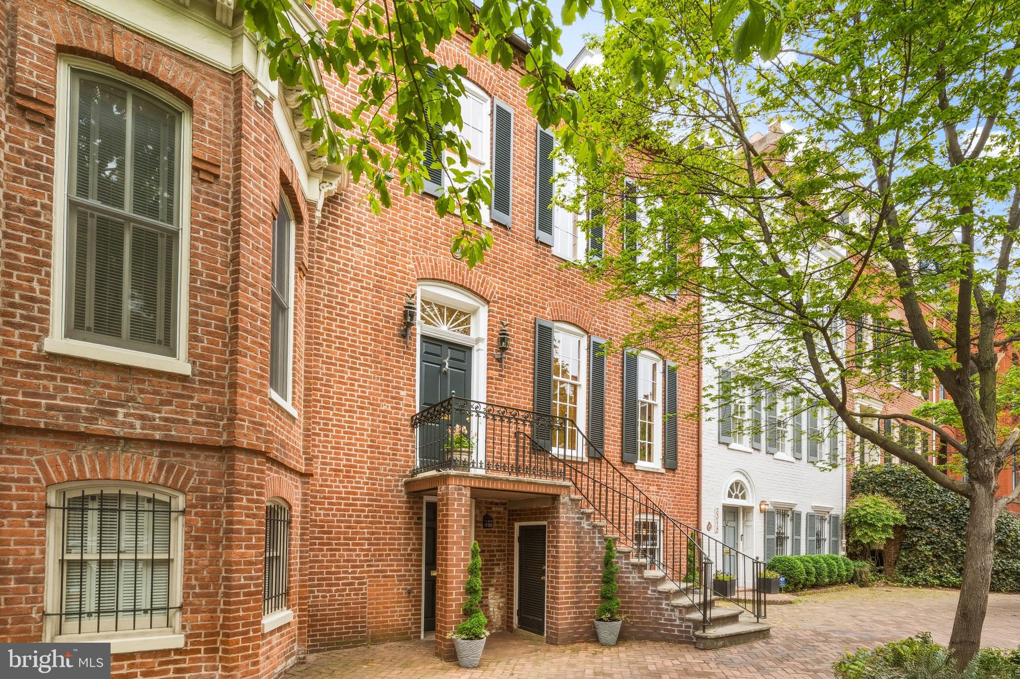 Nestled on one of the most sought-after blocks in Georgetown’s West Village, 3316 N Street NW is a classic flat-front Federal residence that captures the essence of historic Georgetown living: grand in proportion, rich in history, and defined by timeless architectural detail. Featuring 5 Bedrooms, 4.5 Baths, and 7 Fireplaces throughout, complete with 1-Car Rear Parking. Thoughtfully updated to turnkey perfection, the home preserves its original character while seamlessly incorporating modern comforts. Believed to date to circa 1817–1818, the residence reflects a storied lineage tied to early Georgetown families, including John Cox, William Wilson Corcoran, and the Marbury family of Marbury v. Madison fame. Its architectural evolution is evident in the seamless layering of its Federal origins with a later Victorian addition, all carefully preserved and enhanced over time. From the tree-shaded block of N Street, the home is introduced by a sweeping staircase with a classic wrought iron railing. Inside, the main level is defined by original floors, high ceilings, and beautiful natural light from both northern and southern exposures. A gracious vestibule and foyer open to formal living and dining rooms, divided by original bi-fold doors and anchored by twin hand-carved French fireplaces, with Baccarat chandeliers adding a refined touch. A discreet powder room completes this level. The renovated kitchen blends modern function with historic charm, featuring its own fireplace, a Wolf six-burner range, and Miele appliances. It connects to a side entrance that opens directly to a private rear patio surrounded by a mature garden. The rear gate provides access to secure one-car parking beyond, ideal for effortless daily living. Upstairs, the primary suite offers a striking fireplace with a hand-carved French mantel, twin closets, and a light-filled bath with a walk-in shower. A guest room or den showcases a Federal mantel and antique fire-back, while a third bedroom in the Victorian addition enjoys southwest light, a fireplace, and built-ins. The top floor provides flexible bonus space, featuring dormer windows with both northern and southern exposures, and a full bath with a shower/tub. Enjoying its own front street entrance, and rarely situated above grade, the lower level is something special, featuring exposed beams, custom millwork, fireplace, and built-ins all highlighted by professional lighting. The space is perfect for a library or study, completing the level you will find wine storage, laundry, and space for a gym or the perfect guest suite with its own rear entrance! Complete with rear parking with direct access, this is a truly exceptional Georgetown offering on one of the neighborhood's best blocks!