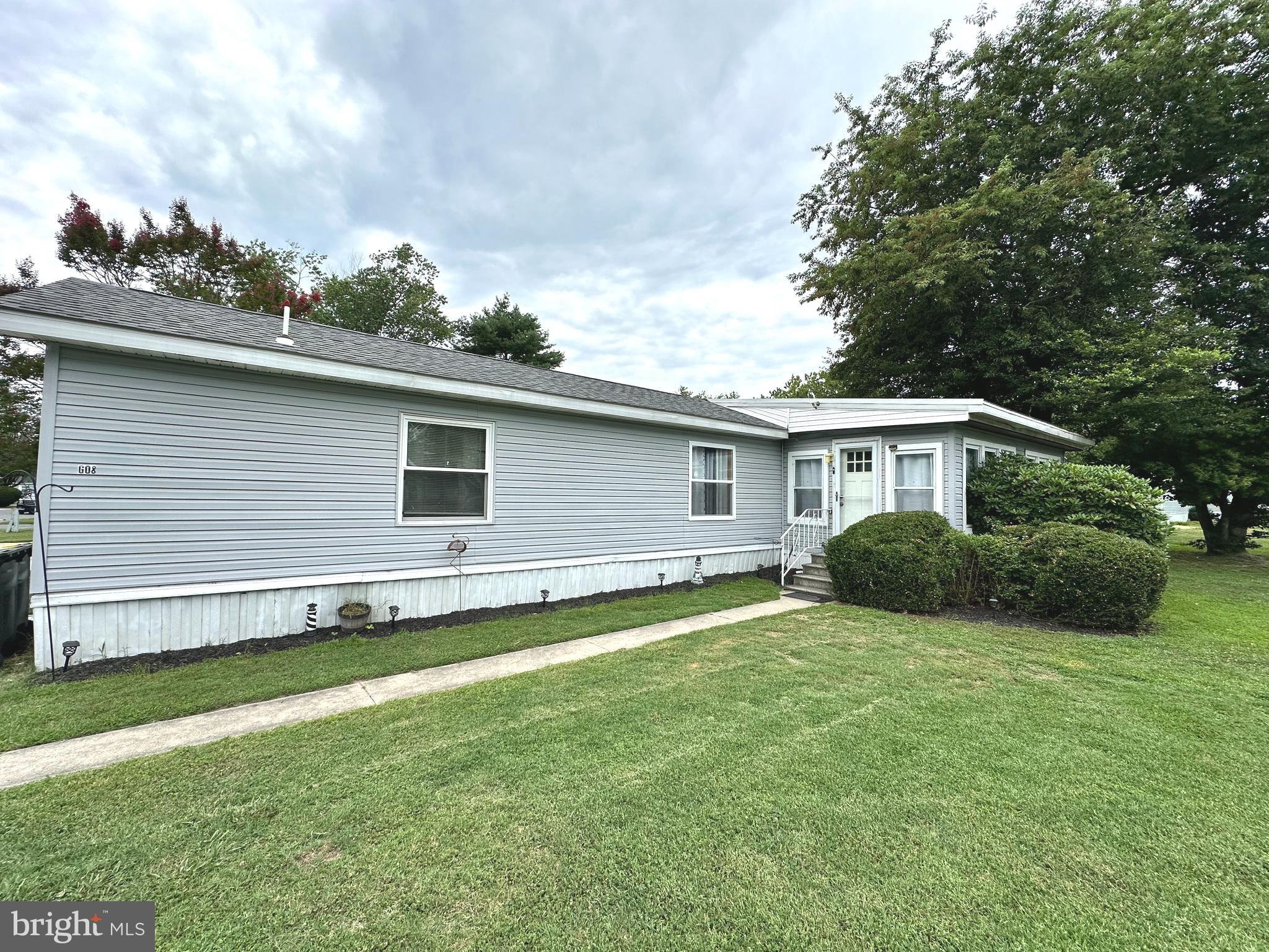 Welcome to 33483 Buttercup St in Angola Beach. This 1982 manufactured home sits on a generous corner lot offering a 2 car off street parking pad and a newer 8x10 barn style shed with double doors for extra storage.
The interior has been updated with luxury vinyl plank flooring throughout. Upon entering the 4 season room through the newer front door and storm door you find an area for either a home office or additional entertaining space. The open concept living room, kitchen area offers recessed lighting for that updated modern feel, Gray kitchen cabinets, bright counter tops and back splash are a few updates along with newer stainless steel appliances. Convenient laundry area with a storage closet hidden by a barn door. The hall bath has been updated with a new walk in shower. The primary bedroom is on the opposite side of the home for a little more privacy and provides an en-suite bath with double sinks and a nice shower. The heating and AC system have been updated within the past 2 years. This is a great opportunity to own a vacation home or full-time residence in Angola Beach. The amenities include 2 pools, renovated clubhouse, a marina with boat ramp, kayak access and a storage yard additional amenities include a playground, basketball and tennis courts and pet areas. Leasehold interest with Lot Rent of approx. $741/mt. (renews annually with any increases capped as per 25 Del. C. Sec 7050-70534. Lot rent includes water, sewer & trash/recycle. The community owner requires an Application from the Buyer and all occupants 18-years-of-age or older, with acceptance based on: 1)Income Verification; 2)Credit Bureau Score (including debt-to-income ratio); 3)Clean Criminal Background Check. Leased-land properties do not qualify for conventional 30-year mortgages, but financing may be available to qualified borrowers from a few Lenders that specialize in installment/chattel loans for manufactured homes on leased land. Buyer will a real estate transfer tax (3.75% DMV Doc Fee) & a Settlement Agent Fee as part of their closing costs.