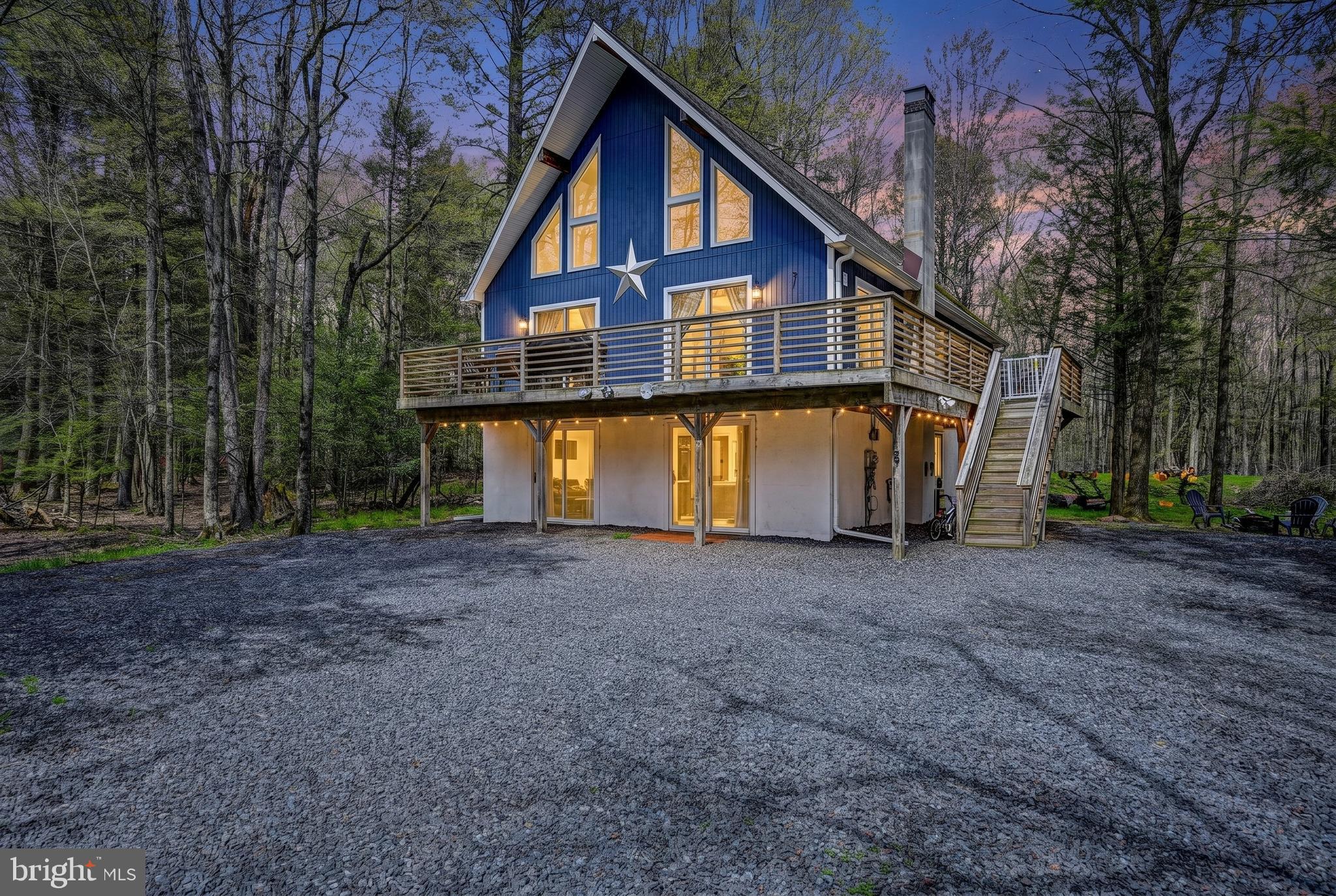 Spectacular  4 bedroom, 2.5 bath chalet with a fully finished walk-out basement is nestled on half an acre in popular Holiday Pocono just minutes from 903, 940 , Lake Harmony, Jack Frost/Big Boulder, & Pocono Raceway.  Easy access to Camelback, Camelbeach, Kalahari, and plenty of shopping at the Crossings Premium Outlets! The sundrenched living room boasts soaring cathedral vaulted ceilings with a dramatic wall of windows & sliders, luxury vinyl plank flooring, stone accent wall highlighting the propane stove, new mini-split, modern ceiling fan and custom wainscoting! The chef's kitchen features white-washed brick backsplash, stainless steel appliances & hood, oversized farmhouse sink, and  butcher block countertops and island.  The elegant dining room has modern chandelier, gleaming LVP floors, and bright sliders to the oversized deck overlooking your lush yard! The expansive family room has a media & game room  with glistening pergo floors & double sliders , convenient first floor bedroom , large powder room, and separate laundry room with storage. Plenty of room to create an in-law or au-pair suite. The awe-inspiring primary suite boasting  vaulted ceilings, custom wallpaper & wainscoting, wall-to-wall carpeting, a remodeled en-suite bathroom with shower,  and sitting room/ library loft that overlooks the great room! The additional lovely bedrooms are also spacious, with plush carpeting, large closets,  neutral paint, and share a renovated hall bathroom complete with granite sink, tile backsplash , modern fixtures, upgraded lighting, and  wide-plank tile flooring . This custom home is an entertainer's delight, with a private backyard oasis backing up to lush woods! Award-winning Jim Thorpe School District!  Enjoy a glass of wine, barbeque with friends, or a warm cup of coffee from the wrap-around deck! This community highlights are the  pristine lakes—one for fishing and the other for swimming—plus a rifle range and other park amenities.Don't miss out on the opportunity to own this magnificent home of  over 2500 sq ft  in the heart of the Pocono Mountains! This peaceful community does not allow STR's so you can bask in the serenity and calm year round!