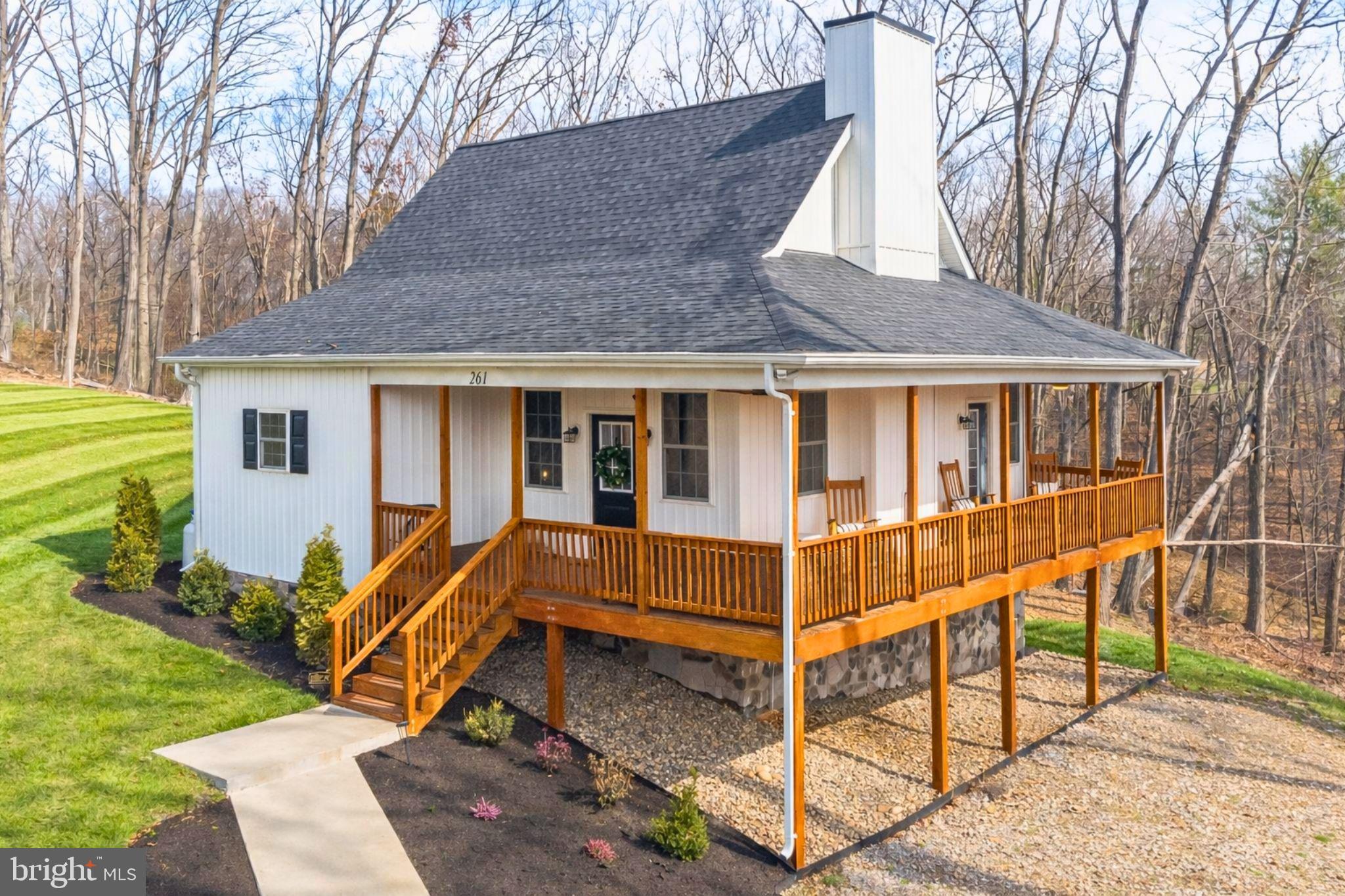 Experience mountain living at its finest in this inviting 3-bedroom, 3.5-bath cottage tucked just outside downtown Front Royal and moments from Shenandoah National Park. 
Surrounded by peaceful wooded scenery and sweeping mountain views, this home offers a true getaway feel while keeping you close to town conveniences.
Step inside to an airy, open layout where rustic charm meets modern ease. The spacious living room is highlighted by soaring vaulted ceilings and a dramatic floor-to-ceiling stone fireplace. Just beyond, a sunlit office with wraparound windows offers an inspiring spot to work or unwind. 
The open-concept dining area and kitchen are designed for connection, featuring stainless steel appliances, sleek white cabinetry, granite countertops, and a large dining space with a stylish green accent wall.
The main level hosts a comfortable primary bedroom with its own private bath, while the upper level provides 2 additional bedrooms, each with its own ensuite, giving family and guests privacy and space to unwind.
The fully finished walkout basement expands your living options even further, offering a large family room, an additional half bath, a spacious bedroom with a full bath and walk-in closet, a separate laundry area, and access to a ground-level patio perfect for outdoor dining or relaxing in the fresh mountain air.
One of the best features of the property is the wide, wraparound porch, your front-row seat to stunning Skyline Drive views. This outdoor space is designed to be enjoyed year-round.
High-speed internet keeps you connected, while nearby wineries, historic attractions, and the charming shops and restaurants of Front Royal provide endless ways to explore the area. The community also has private access to the Shenandoah River, where you can kayak, fish, swim, or simply enjoy peaceful riverfront moments.
With easy access to I-66 and major commuter routes, the location is ideal for everyday living or frequent travel. The home also operates as an Airbnb, making it a great choice for a primary residence, weekend getaway, or investment property.