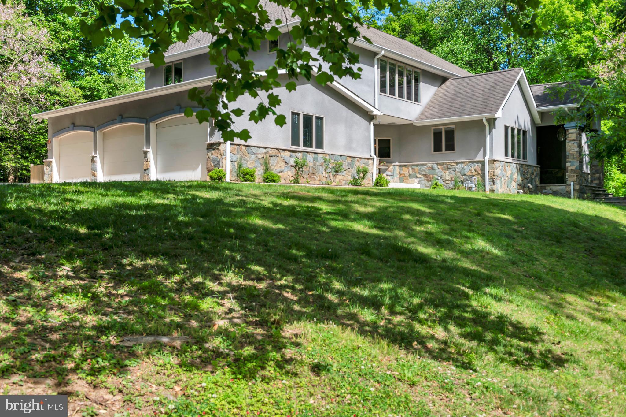 Introducing an extraordinary custom-built estate privately nestled on more than 2+ WOODED ACRES along the B&A Trail in a quiet cul-de-sac setting, just minutes from downtown HISTORIC ANNAPOLIS and convenient to the Rt. 50 corridor.   Located in the sought-after Broadneck School District, this exceptional property also includes deeded mooring rights to Cool Spring Cove.
Designed for both elegant entertaining and comfortable everyday living, the home showcases a dramatic two-story great room highlighted by an impressive 18-foot stone fireplace and expansive windows that fill the space with natural light.   The OPEN-CONCEPT layout seamlessly connects the living, dining, and gourmet kitchen areas, with quartz countertops and a gas range with double ovens create the perfect culinary setting.
Tailored for MAIN-LEVEL LIVING, the spacious primary suite offers a private retreat complete with a spa-inspired bath featuring a walk-in shower/steam room, jacuzzi tub, and oversized walk-in closet.   The main floor also includes a flexible guest bedroom or office, a half bath, and an expansive laundry/mudroom adjoining the oversized three-car garage and workshop with custom cabinetry.
A stunning curved open staircase leads to the upper level, where a second primary suite provides ideal MULTI-GENERATIONAL LIVING accommodations, accompanied by two additional bedrooms connected by a Jack-and-Jill bath.
The  FINISHED LOWER LEVEL significantly expands the home’s living space with a large recreation room centered around an 11-foot stone fireplace, along with a custom bar, gaming area, bonus room or optional sixth bedroom, luxury full bath, and extensive storage and wine cellar space.
OUTDOOR LIVING is equally exceptional, featuring a sprawling illuminated patio designed for year-round entertaining. The fully equipped outdoor kitchen includes a pizza oven, burners, sink, mini refrigerator, and adjoining firepit area. Thoughtful upgrades throughout — including a whole-house generator — complete this truly one-of-a-kind property.