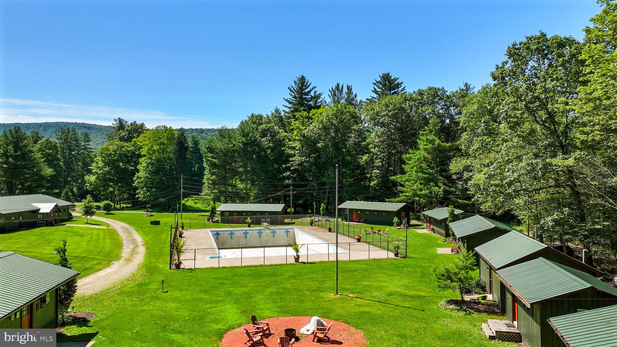 Own a destination with built-in income at Elk Creek Escape—nestled in the scenic mountain setting of Hillsgrove, just 31 miles from Williamsport. Tucked in a quiet valley setting in, this turnkey campground offers over 20,000 square feet of infrastructure with a wide mix of accommodations and amenities, including 27 RV sites (23 with full hookups).

The property features two 2-story farmhouses suited for caretakers or short-term rentals, nine guest cabins, a commercial kitchen and dining hall, game room, covered pavilion, laundry facilities, pool, restrooms, and shower houses. Multiple water sources—including Joe’s Run, Elk Creek, and Loyalsock Creek—run through the property, offering recreation, trout fishing, and a private kayak/canoe launch.

Guests can choose from RV sites, tent and glamping areas, and boondocking options, creating flexibility for a range of experiences. The location provides easy access to Loyalsock State Forest, Ricketts Glen State Park, and Worlds End State Park, making it well-suited for weddings, reunions, corporate retreats, and group getaways.

Formerly known as Green Acres Baseball Camp—a Little League camp operating from 1973 to 2010—this property carries a long-standing history as a destination retreat. With ballfields, established accommodations, repeat visitors, and event-ready infrastructure already in place, Elk Creek Escape presents a strong opportunity for ongoing income in a naturally appealing setting.