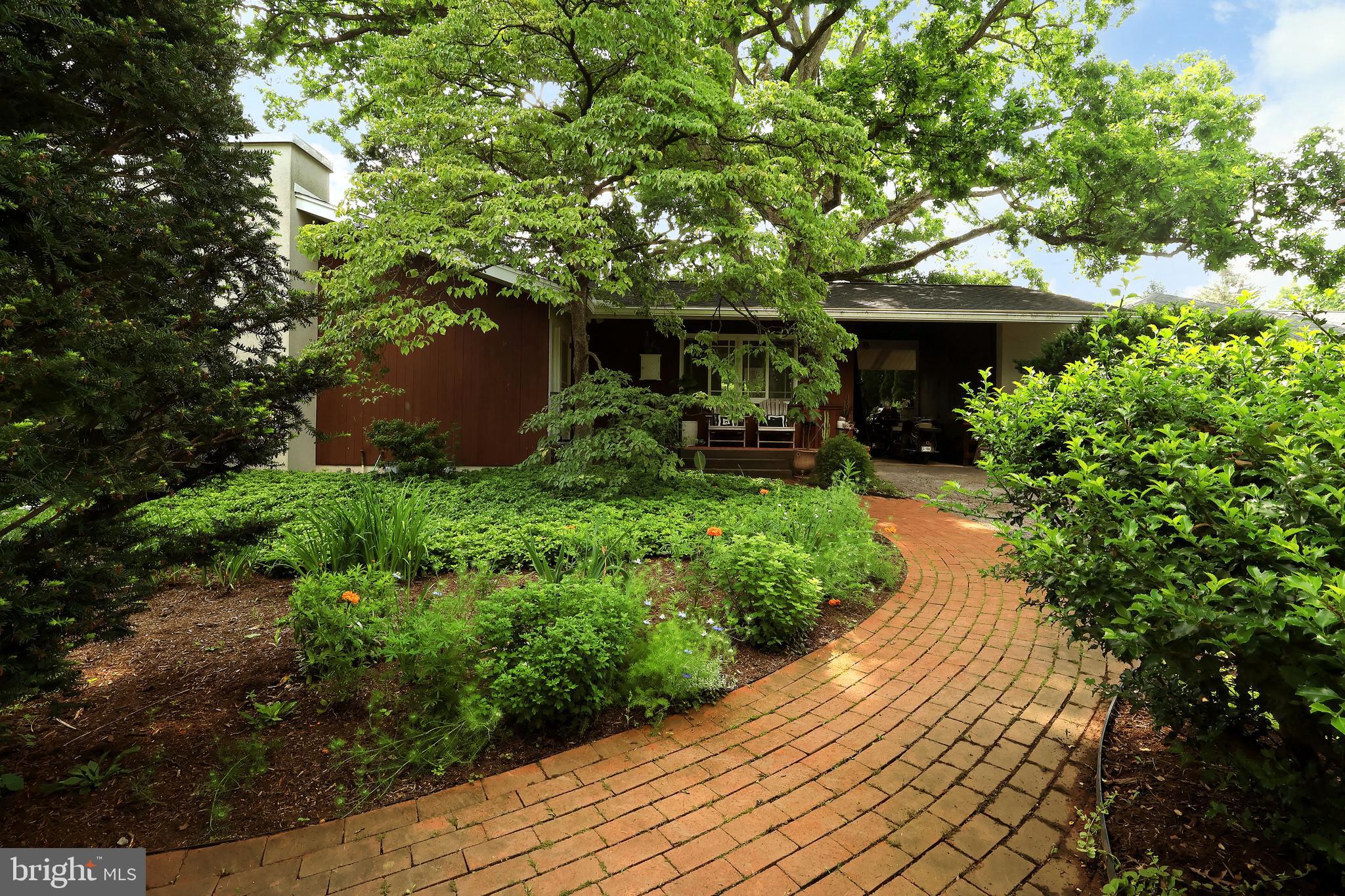 We know you love a fabulous mid-century! 284 E. McCormick Ave, a quiet spot in the Highlands, will not disappoint. Framed by an incredible, over 200-year-old, historic white oak from the original farm fields, this darling 3 bed/1.5 bath ranch was designed by PSU architecture professor Phil Hallock and holds all of yesteryear's charm while having been lovingly updated with modern amenities. The no-mow front gardens welcome you with wonderful perennial plantings; a gardener's delight. Step through the foyer into the wonderfully light and bright open floor plan with stunning hardwood floors and large windows! The centerpiece of the home is the sophisticated vaulted living room featuring a wood-burning fireplace with floor-to-ceiling exposed white brick, beautiful modern chandelier, exposed beams, built-ins, and hardwood floors. You'll love entertaining in the open dining room with lovely built-in cabinets and a door to the back gardens. Perfectly darling, the updated galley kitchen is just the space you need to whip up culinary masterpieces and features beautiful quartz countertops, SS appliances, subway tile backsplash, LVP flooring, well-appointed white cabinets with oiled bronze hardware, recessed lighting, and a small pantry closet. Cozy up with a good book and a cup of tea in the lovely den with exposed beams, brick surround gas stove, a sliding door to the back yard, and new hardwood floors. You'll appreciate having a sweet vintage half bath for guests, a double-wide hallway linen closet, and pull-down attic access! The three bedrooms are versatile in usage and all feature hardwood floors. The primary bedroom has a larger double closet and built-in mirrored wall surrounding lovely sized windows! A great option for a home office or studio, the 2nd bedroom features built-in shelves and a closet! And the third bedroom features a large window with a cool extended sill creating a neat shelf along the main wall. Ceramic tile floors and a tub/shower combo can be found in the shared hall bath with single vanity and built-in storage system. Downstairs you'll find extra space in the old school rec room great for rainy day play or hobby space. You'll also appreciate the unfinished area with laundry, lots of storage, and the mechanicals including a 2023-installed gas boiler and hot water heater. The home is also equipped with central air for summertime comfort. Outside you'll find a whimsical landscape of cottage style gardens with raised beds and walking paths in the delightful fenced yard. Enjoy a sunny afternoon on the small brick patio or gardening until your heart is content! The carport provides covered parking or a great breezeway! Located in the borough, the Highlands is a highly desirable quintessential State College neighborhood for its proximity to all the fun of downtown, a quick commute to campus, and sweet history of homes. Come discover all there is to love about this special property today!